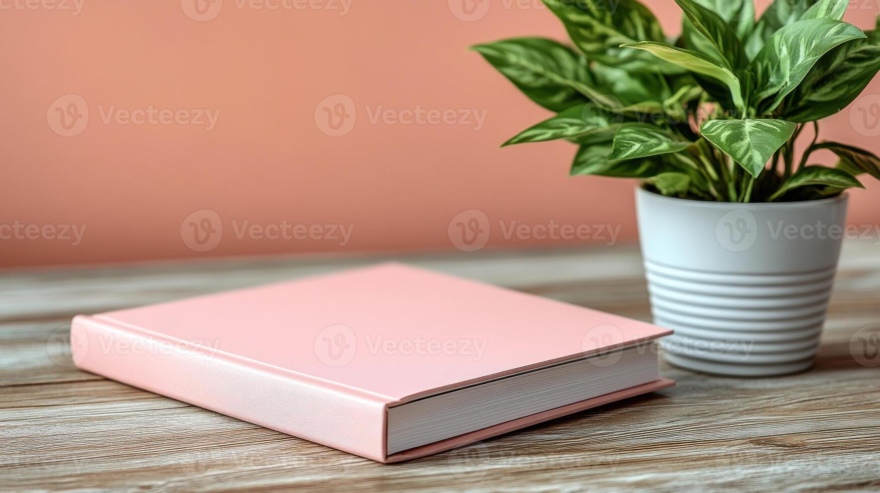 A pink book rests elegantly beside a vibrant green plant, showcasing tranquility and simplicity photo