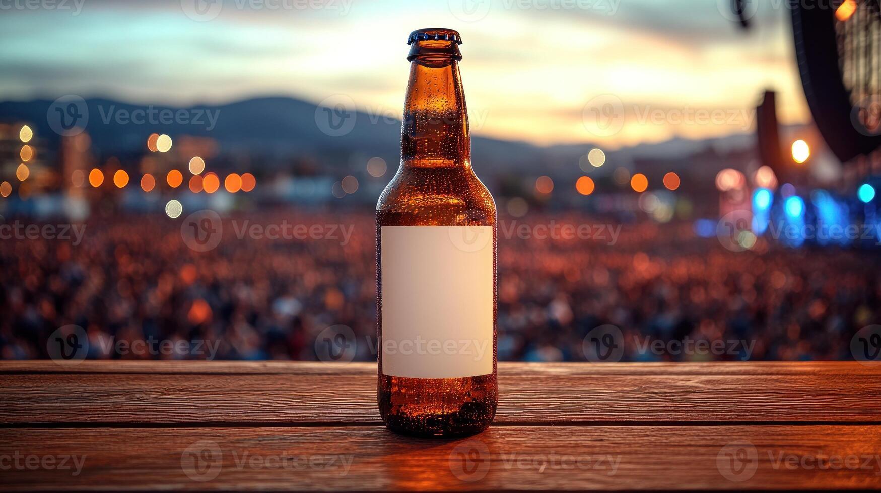 A cold, amber bottle rests on a wooden surface, with a lively crowd enjoying a sunset backdrop photo
