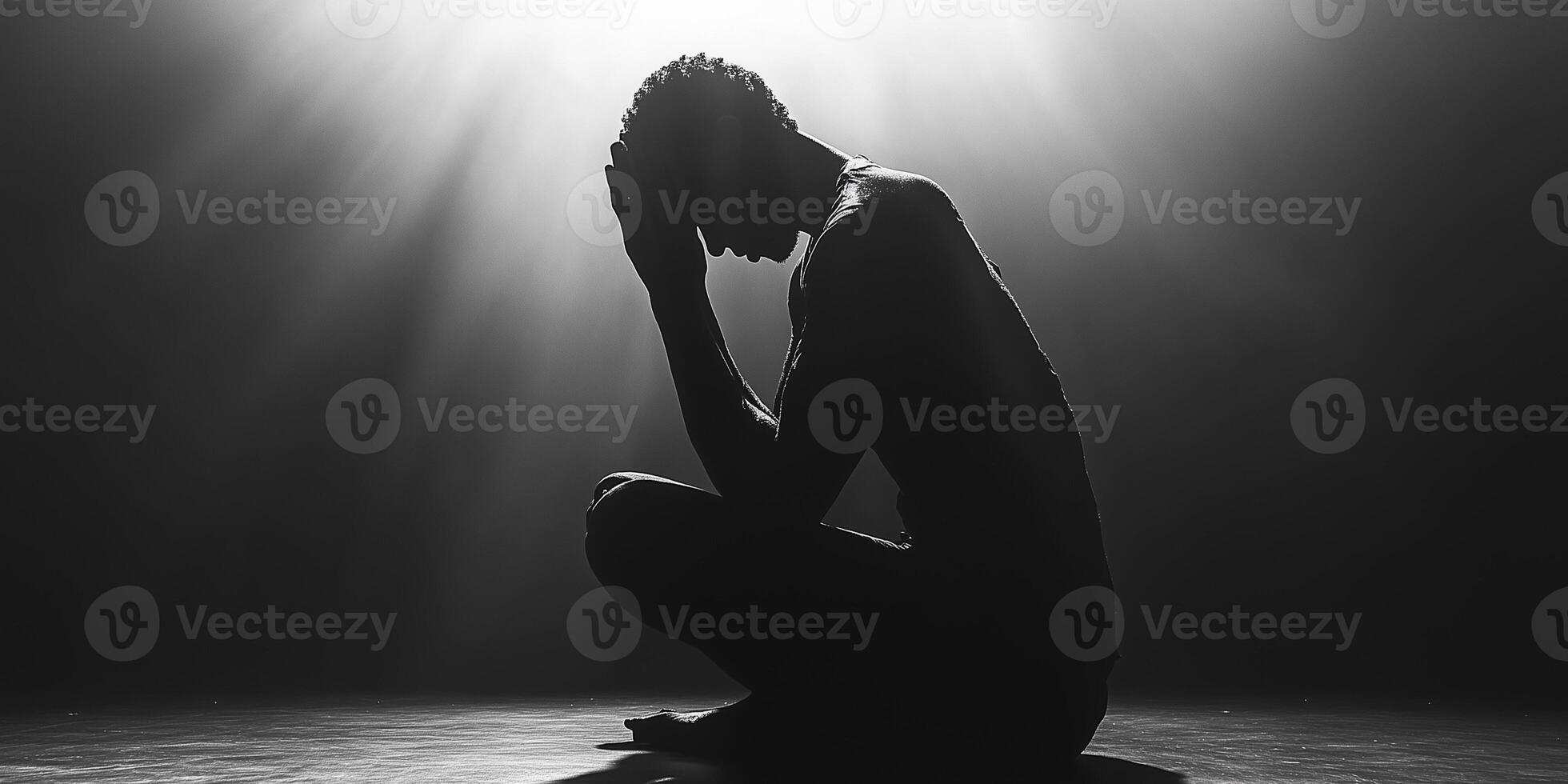Lonely man praying in dark room with light beams photo