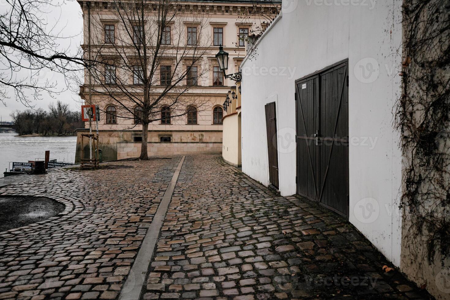 Cobblestone street leading to vltava river in prague near charles bridge on Kampa photo