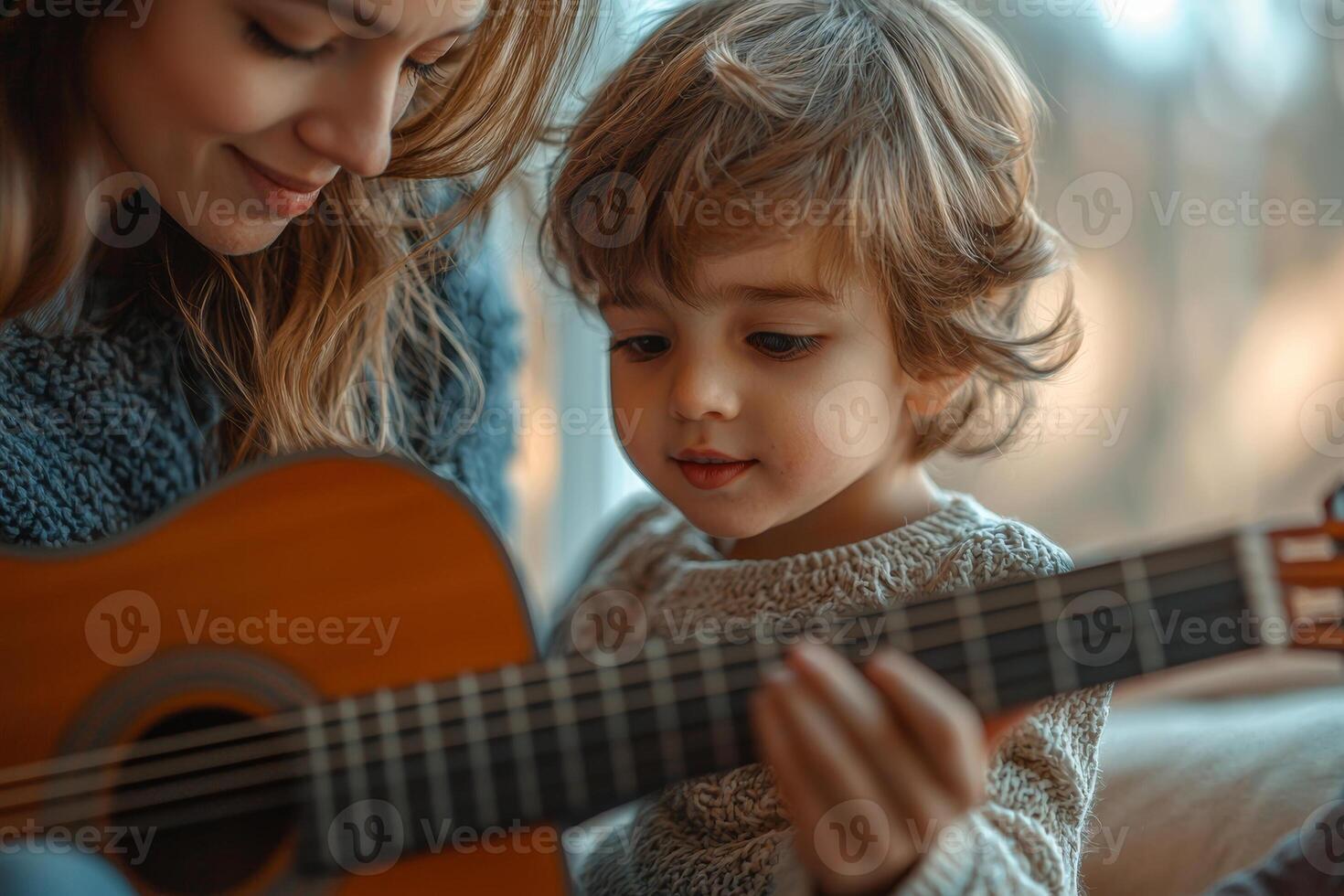 A mother teaches her young son to play guitar on a cozy afternoon at home, sharing a moment of musical bonding and joy photo