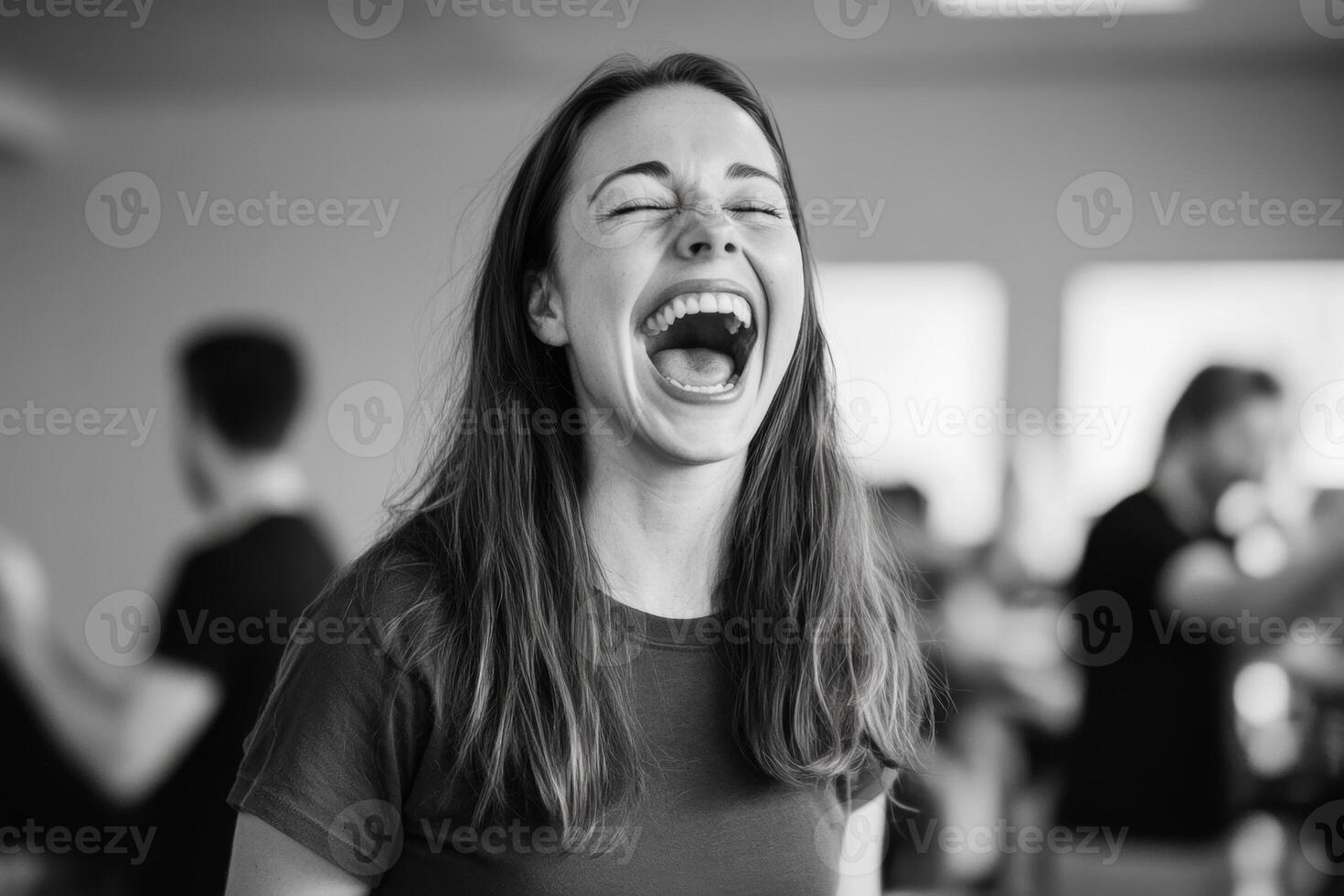Happy young woman laughing in a lively indoor setting filled with people engaged in conversation and activities photo