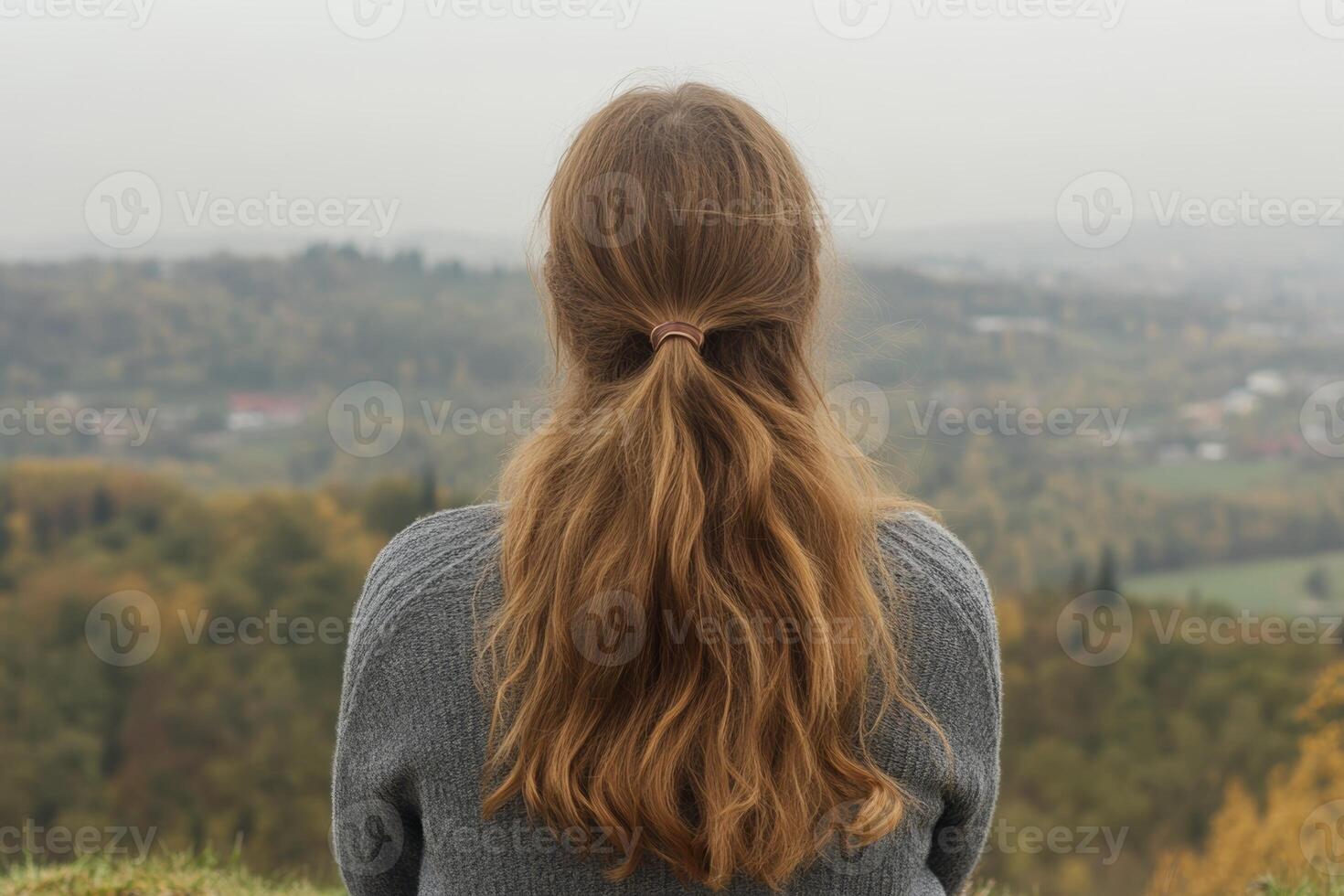 A person gazes out over a misty valley adorned with autumn foliage during a quiet afternoon in the countryside photo