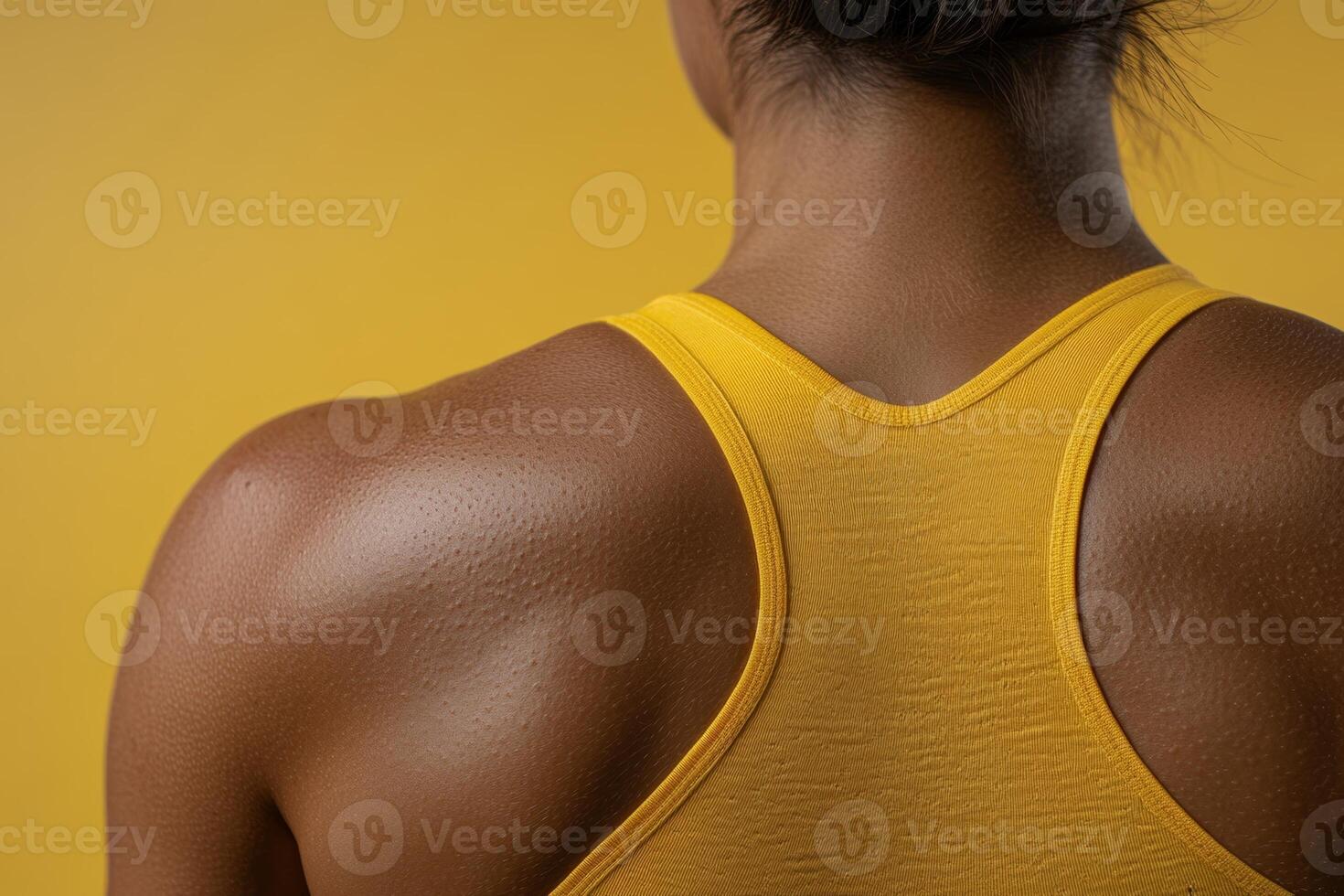 Active woman showcasing toned shoulders and back against a vibrant yellow background during a workout session photo