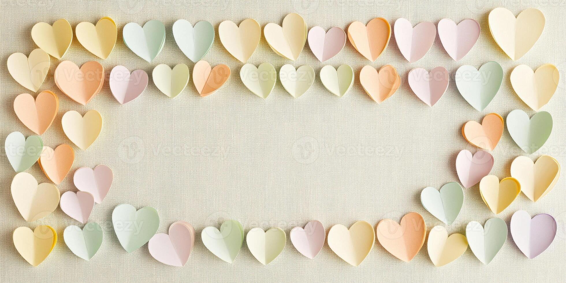 Pastel paper hearts in various soft colors forming a heart-shaped border on beige background photo