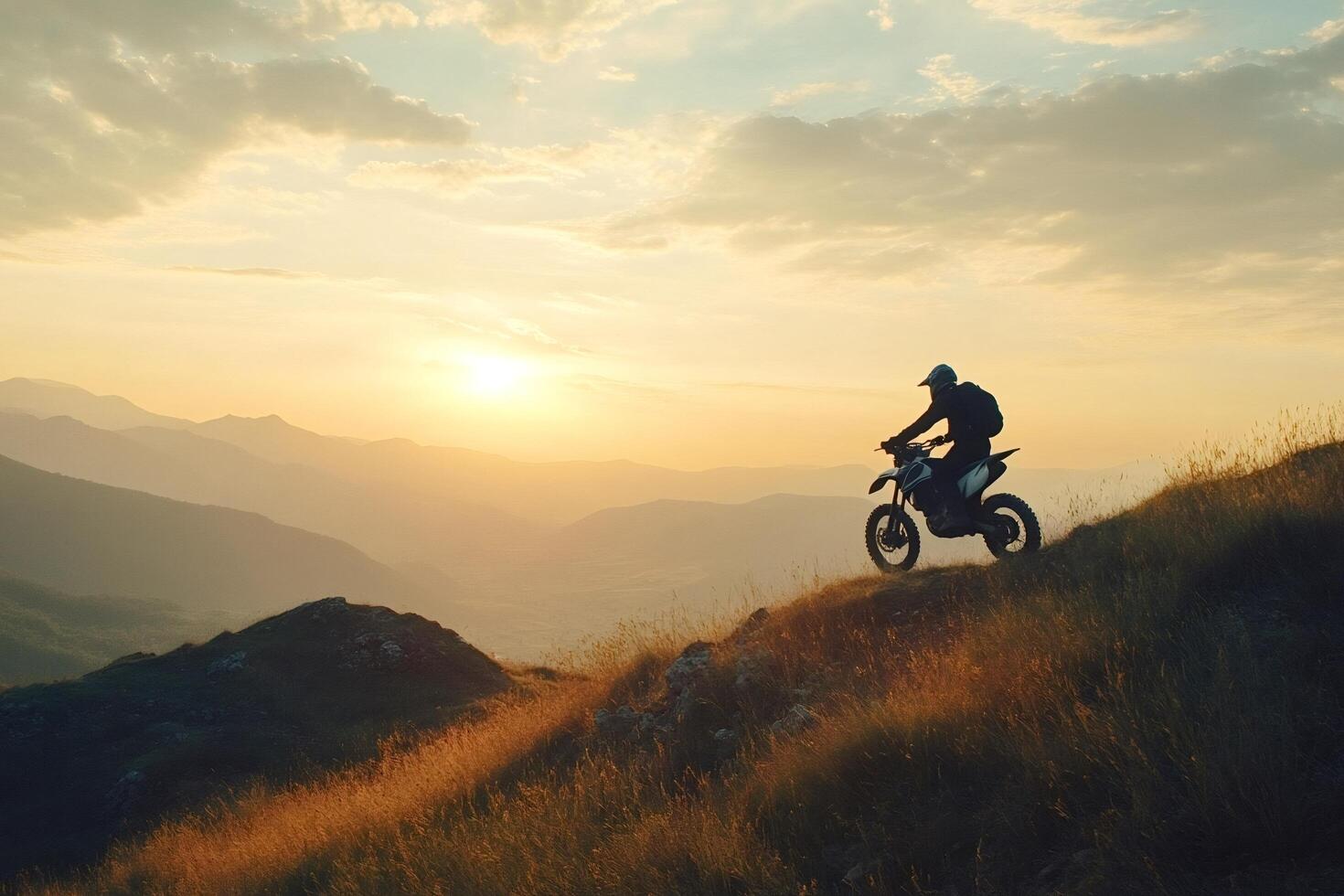 Motorcyclist riding on mountain ridge at sunset photo