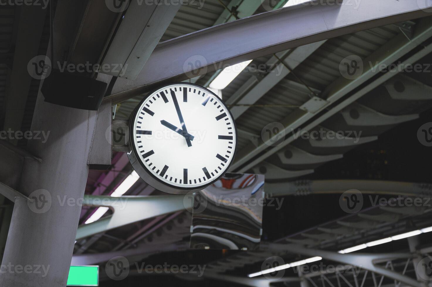 White simple clock hanging on pole in station photo