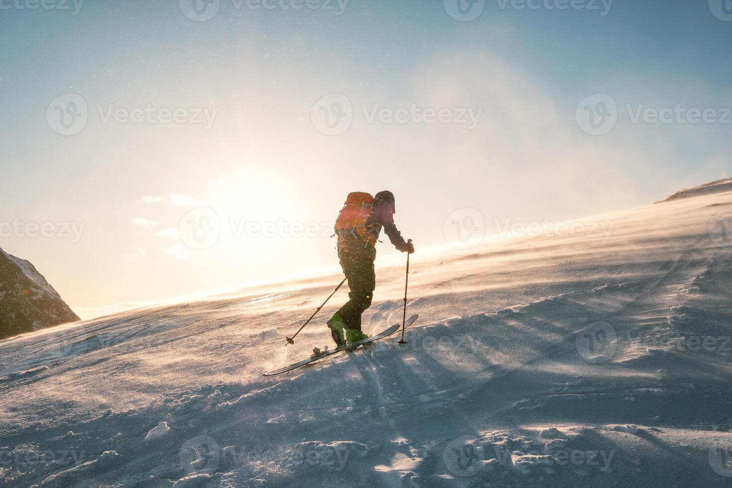 Man skier with backpack trekking on snow mountain with sunlight photo