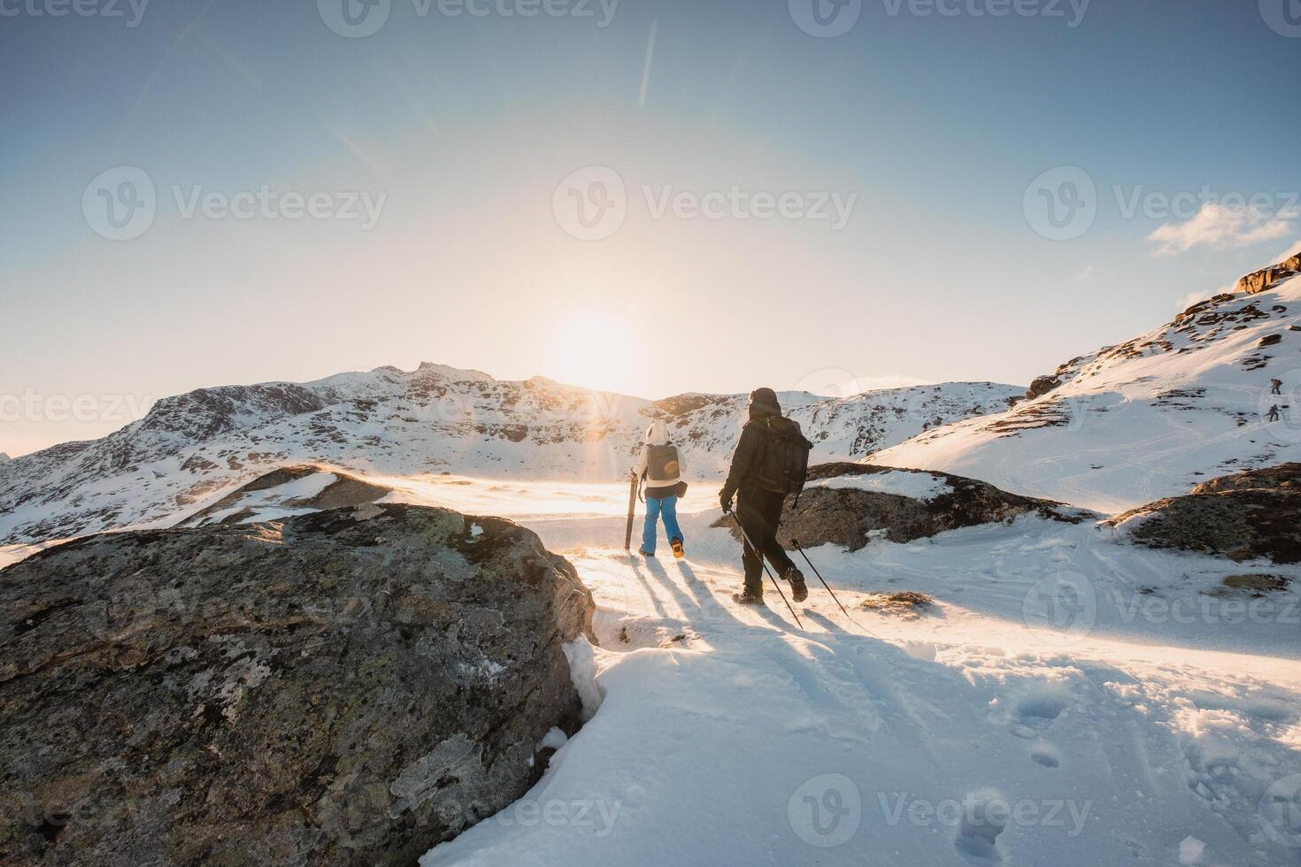 Two mountaineer hiking to peak mountain on snow field at sunset photo
