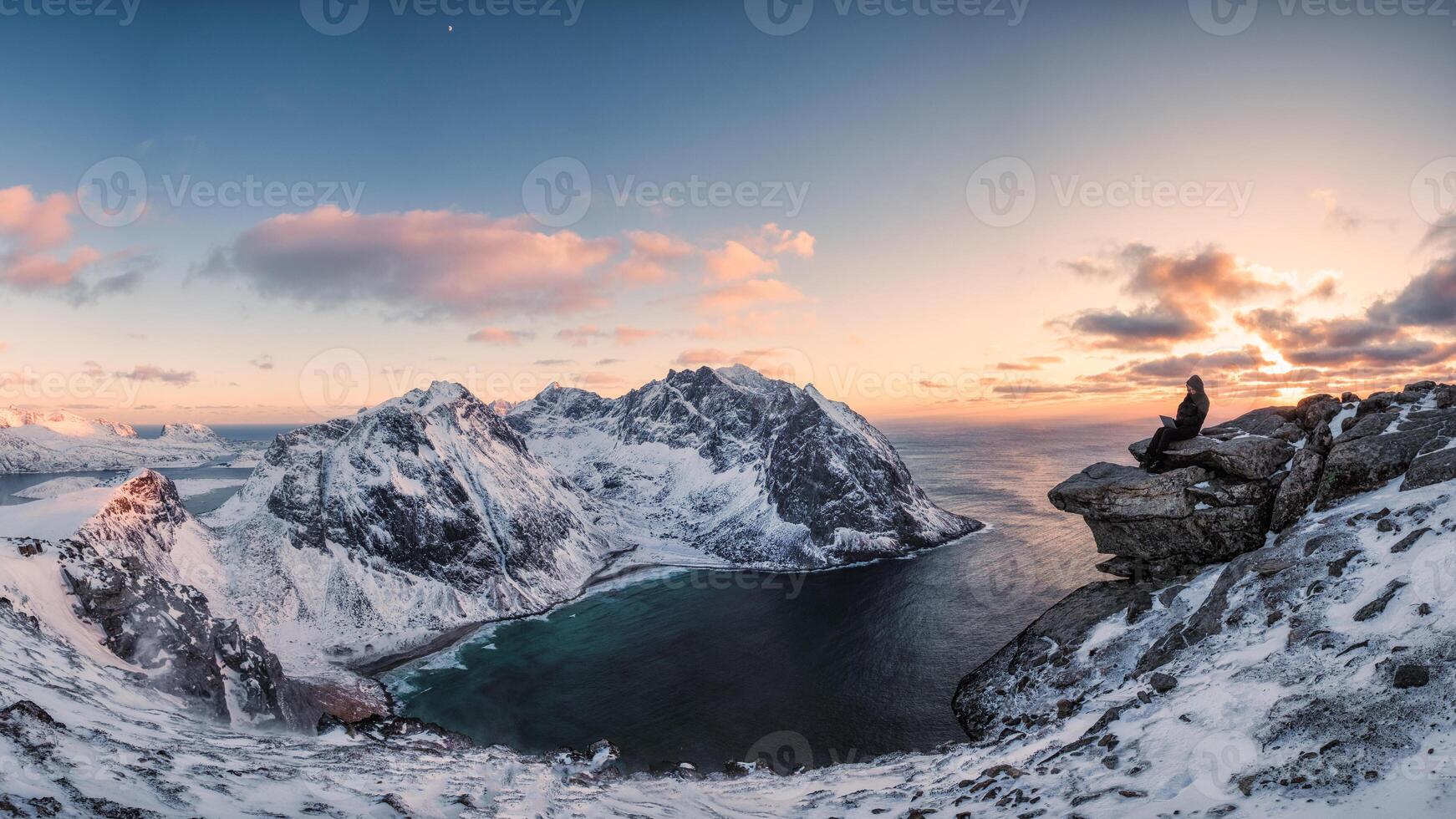 Panorama of Mountaineer sitting on rock on peak mountain of arctic coastline photo