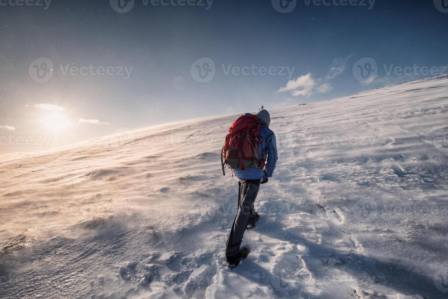 Man mountaineer climbing to the peak mountain on winter at sunset photo