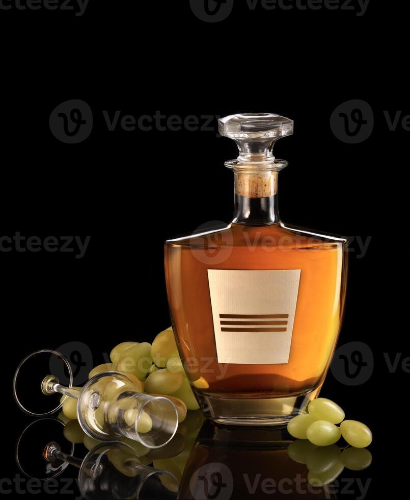 a bottle of whiskey and grapes on a black background photo