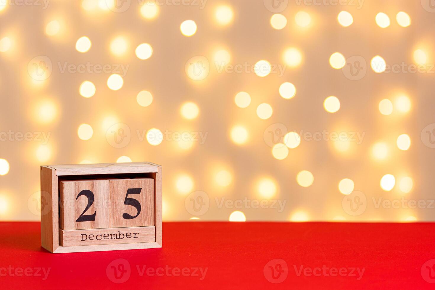 christmas wooden calendar 25 december on red background and lights background photo