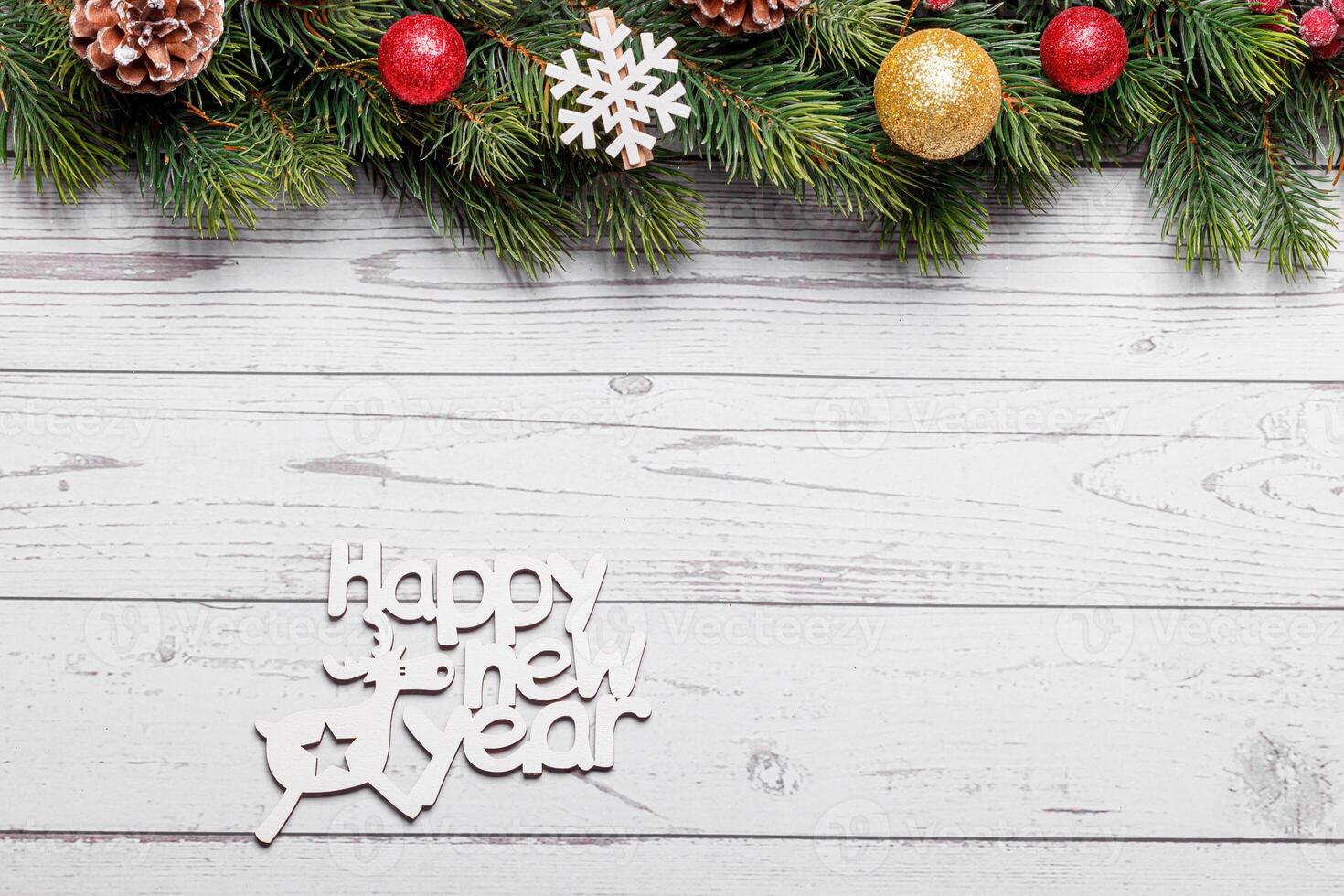 close up beautiful branches of a Christmas tree with cones and toys on a white wooden background with the inscription Happy New Year photo
