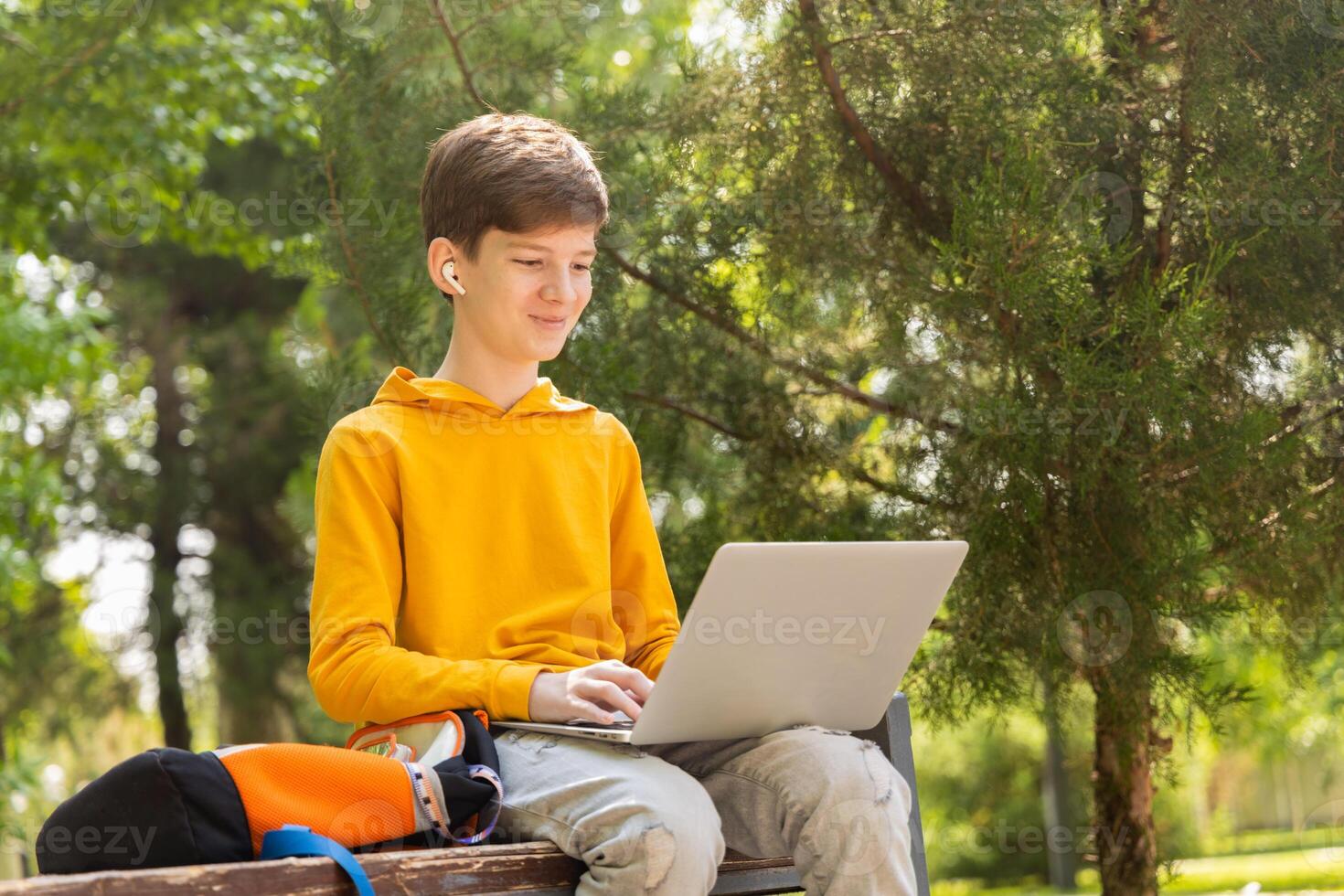 Smiling caucasian boy using laptop. Holding and using a laptop on a sunny spring day, outdoors. photo