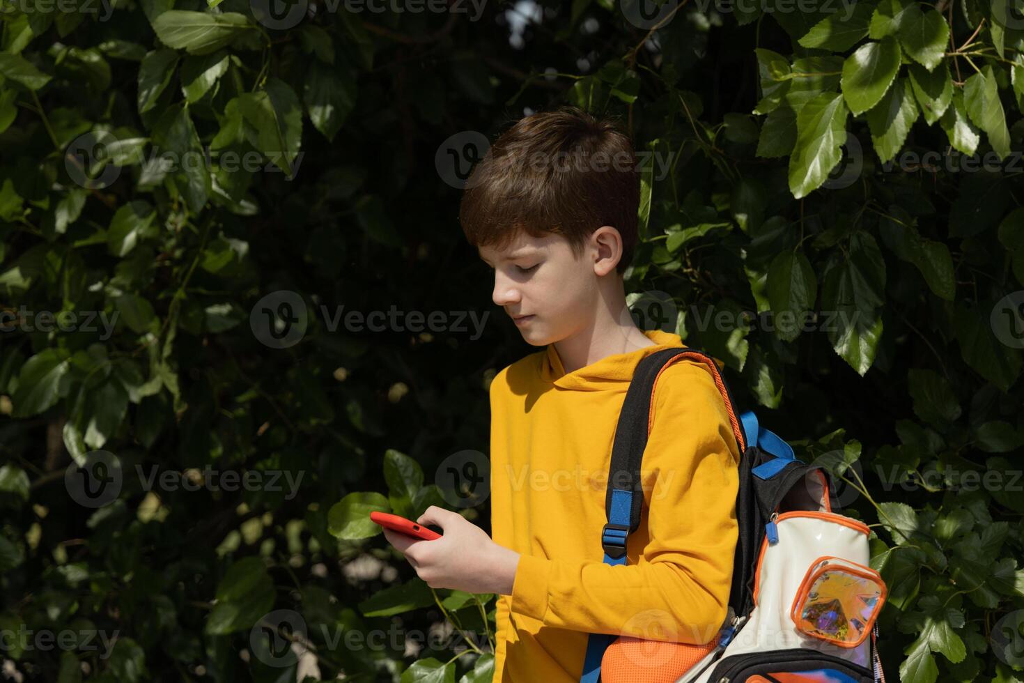 Young fashionable student guy with backpack using mobile phone outside. A lot of copy space. photo