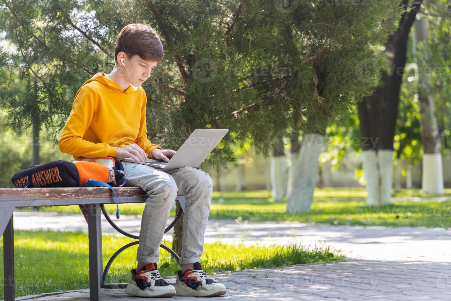 Young smiling boy using a laptop computer outdoors. photo
