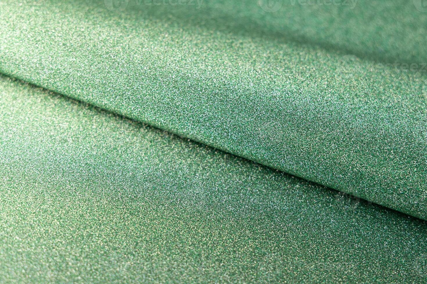 Green shiny glitter paper texture. Shining luxurious fabric. Glimmering light green color st Patric, christmas background. photo