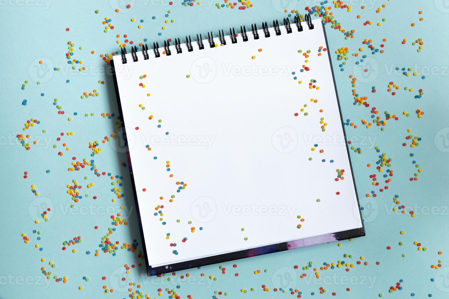 Mock up of empty sketchbook on bright vibrant background with colorful confetti. Copy space. photo