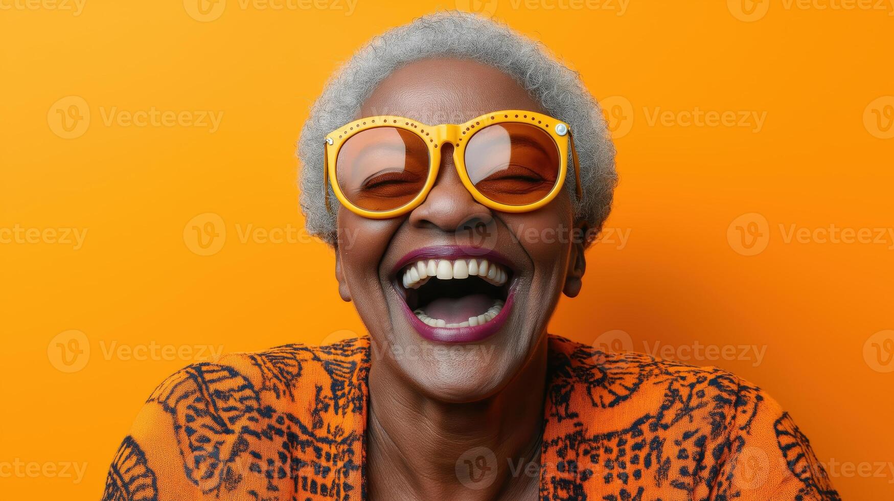 Joyful senior Black woman laughing against a vibrant orange backdrop. Concept of happiness and bold style photo