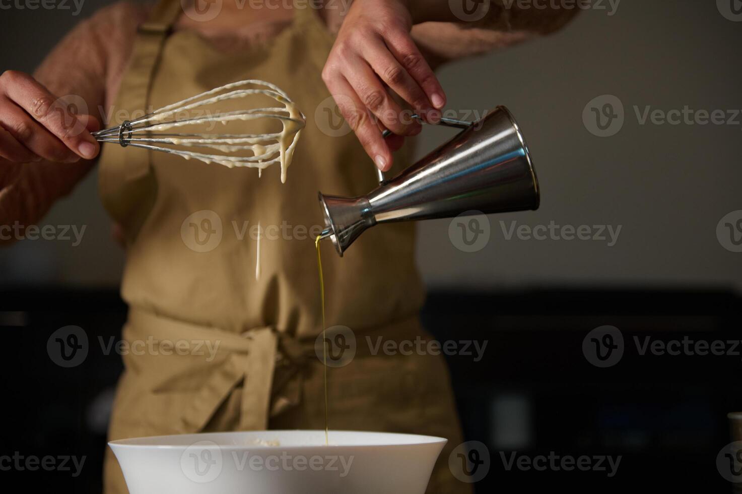 Close-up of hands preparing ingredients during cooking with a whisk and oil. photo