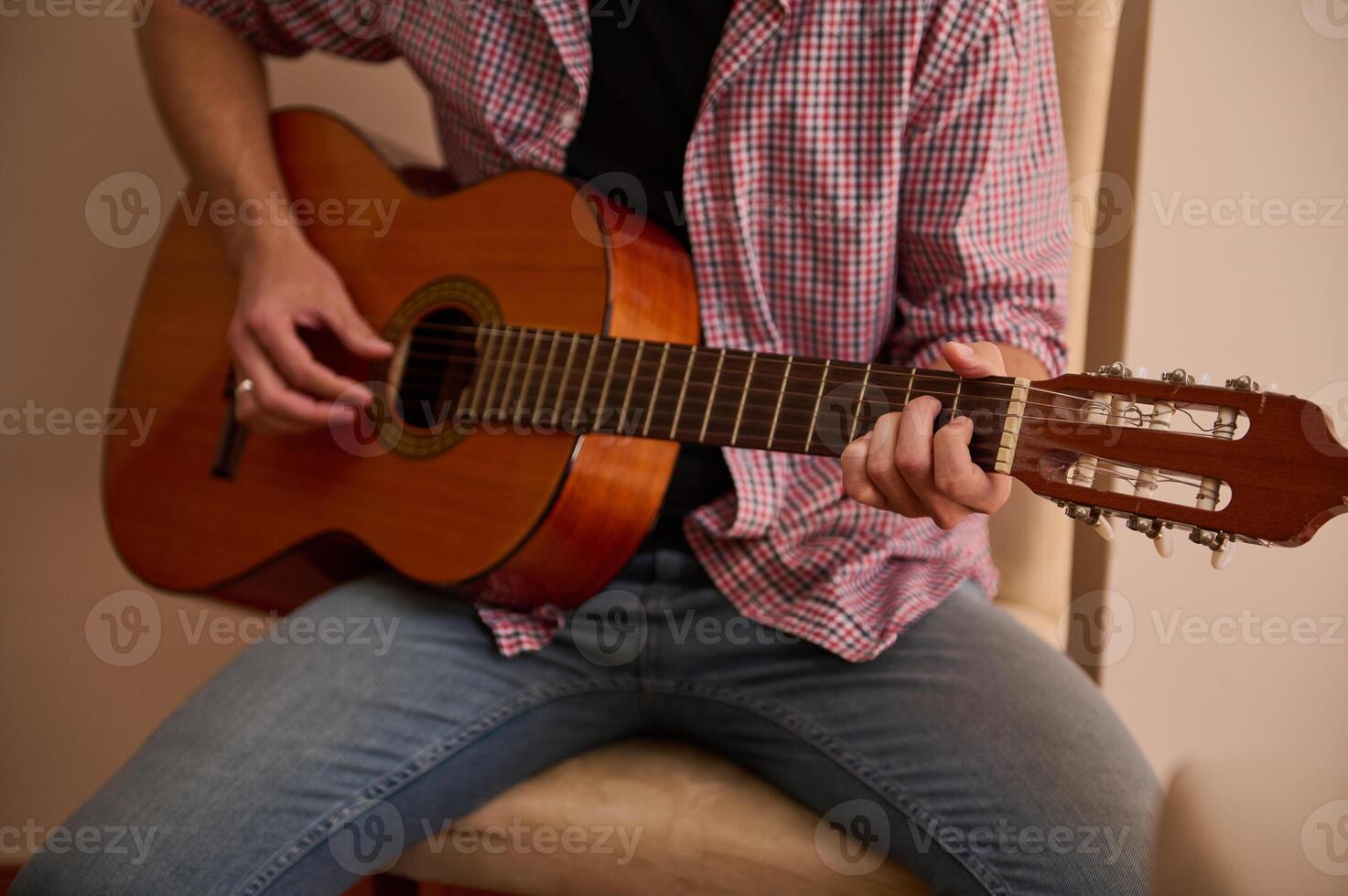 Man playing a classical guitar while sitting indoors relaxedly photo