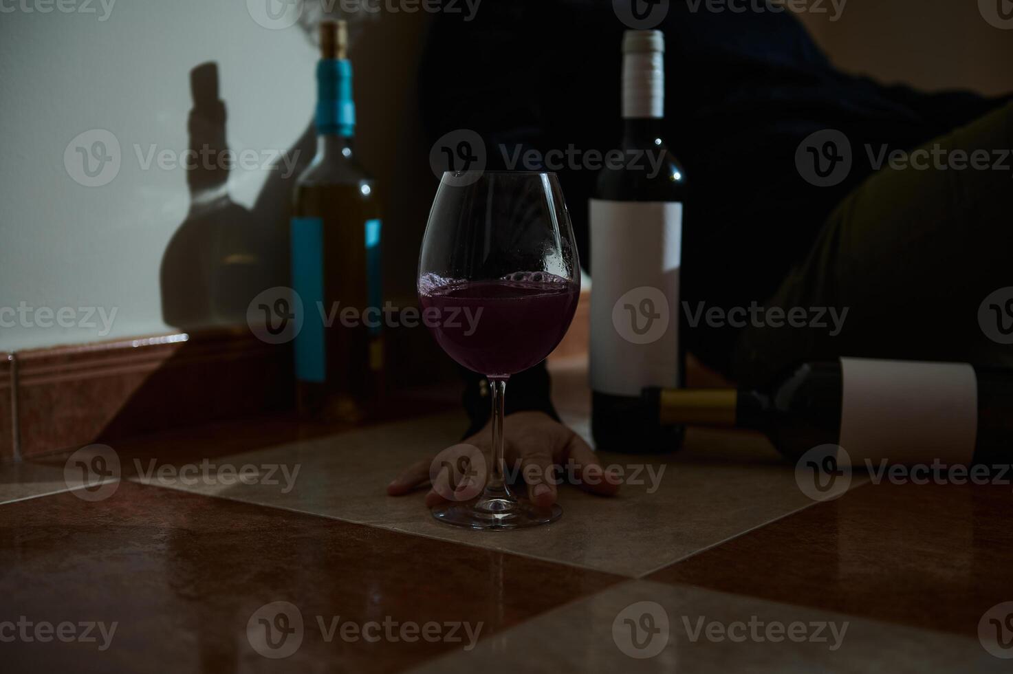 Red wine glass and empty bottles on a tiled floor photo