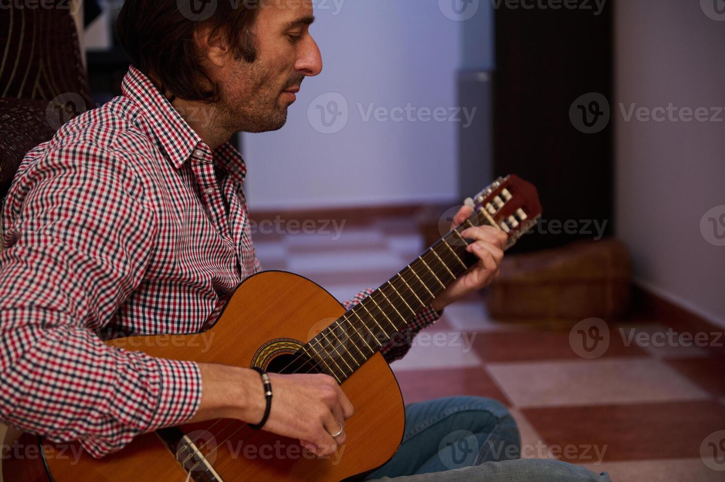 Man playing classical guitar indoors creating a relaxing and musical ambiance photo