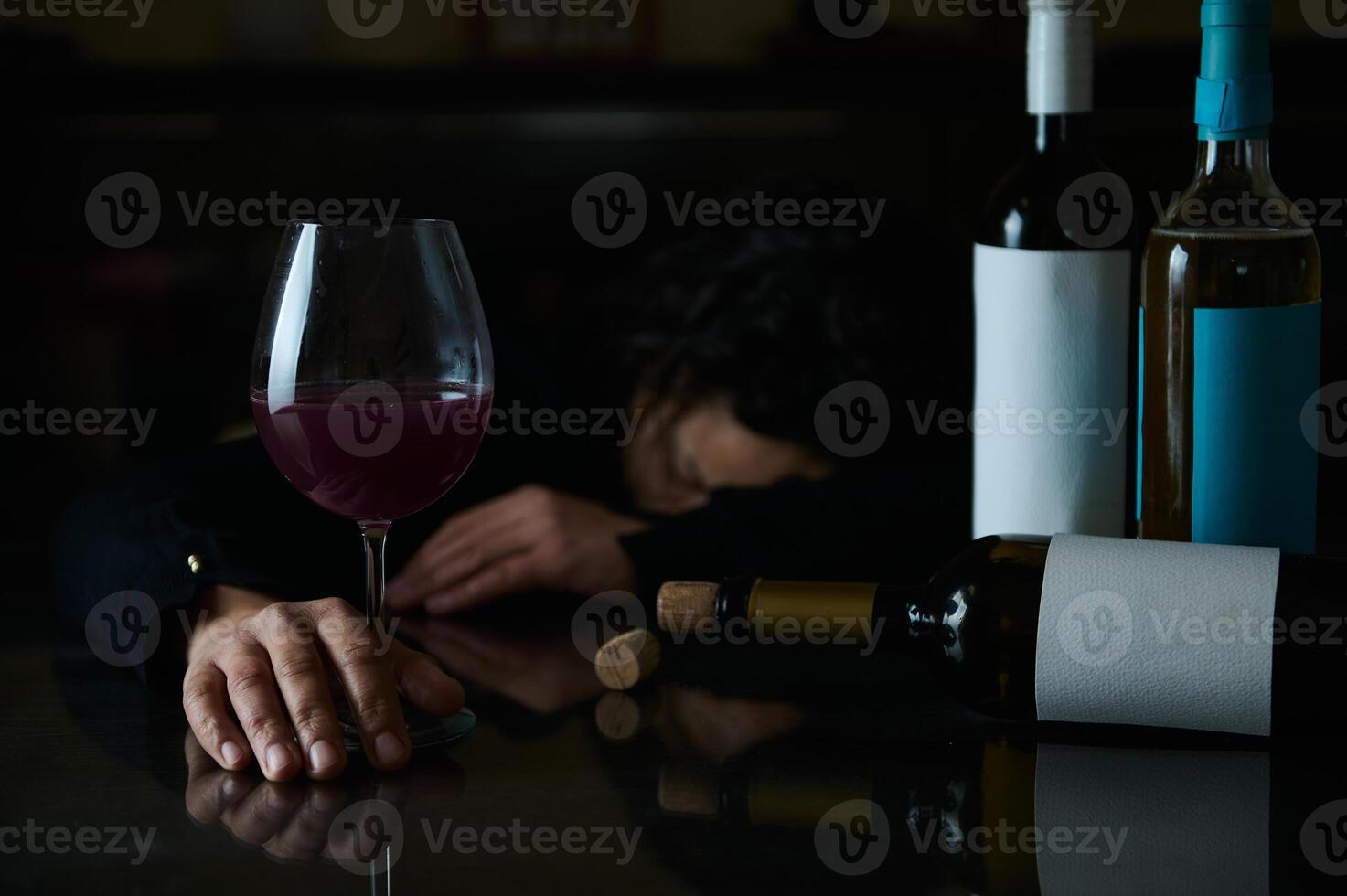 A person experiencing the effects of alcohol consumption in a somber setting photo