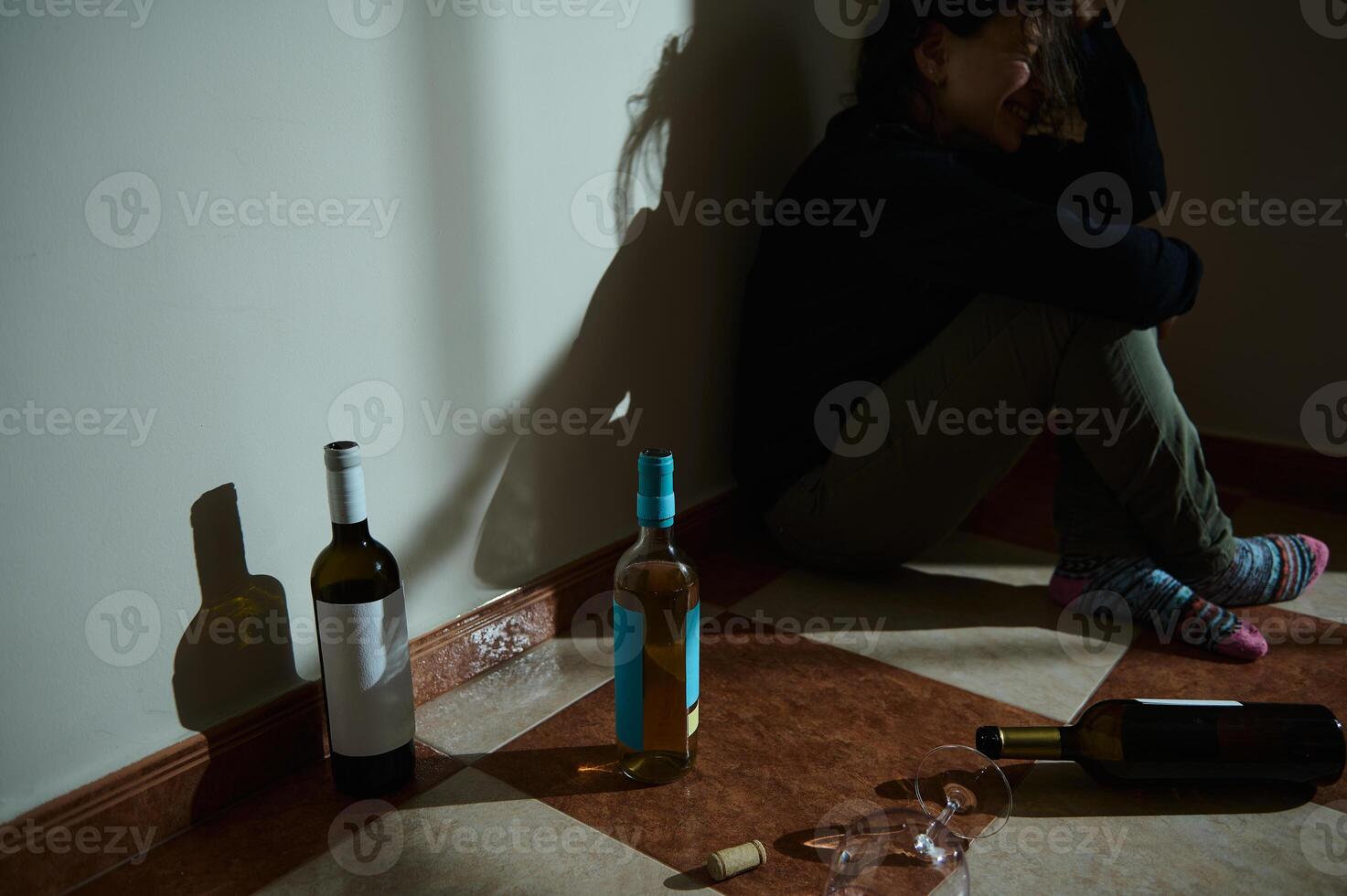 Woman sitting on the floor surrounded by multiple empty wine bottles photo