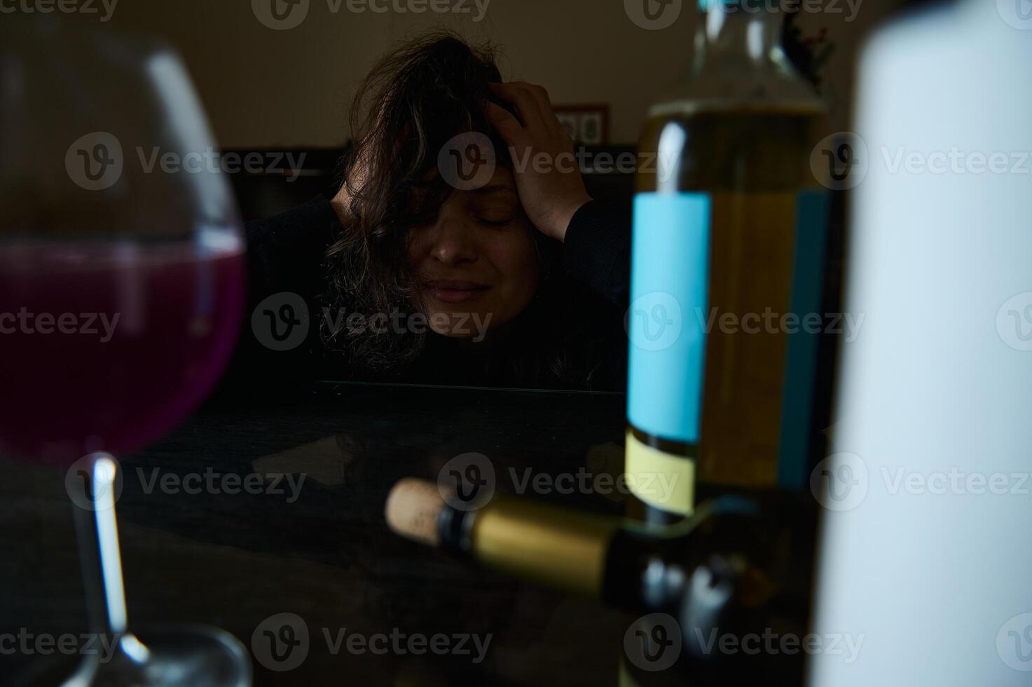Distressed woman with wine bottles conveying struggle and emotional despair photo