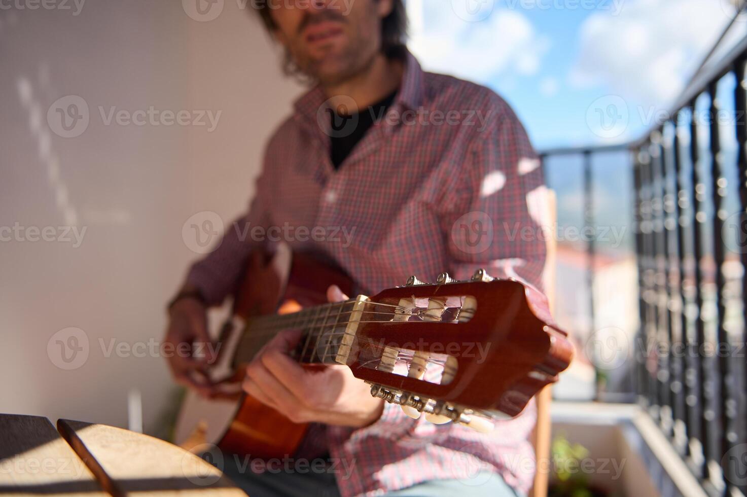 Man playing guitar on a balcony with a relaxed atmosphere photo