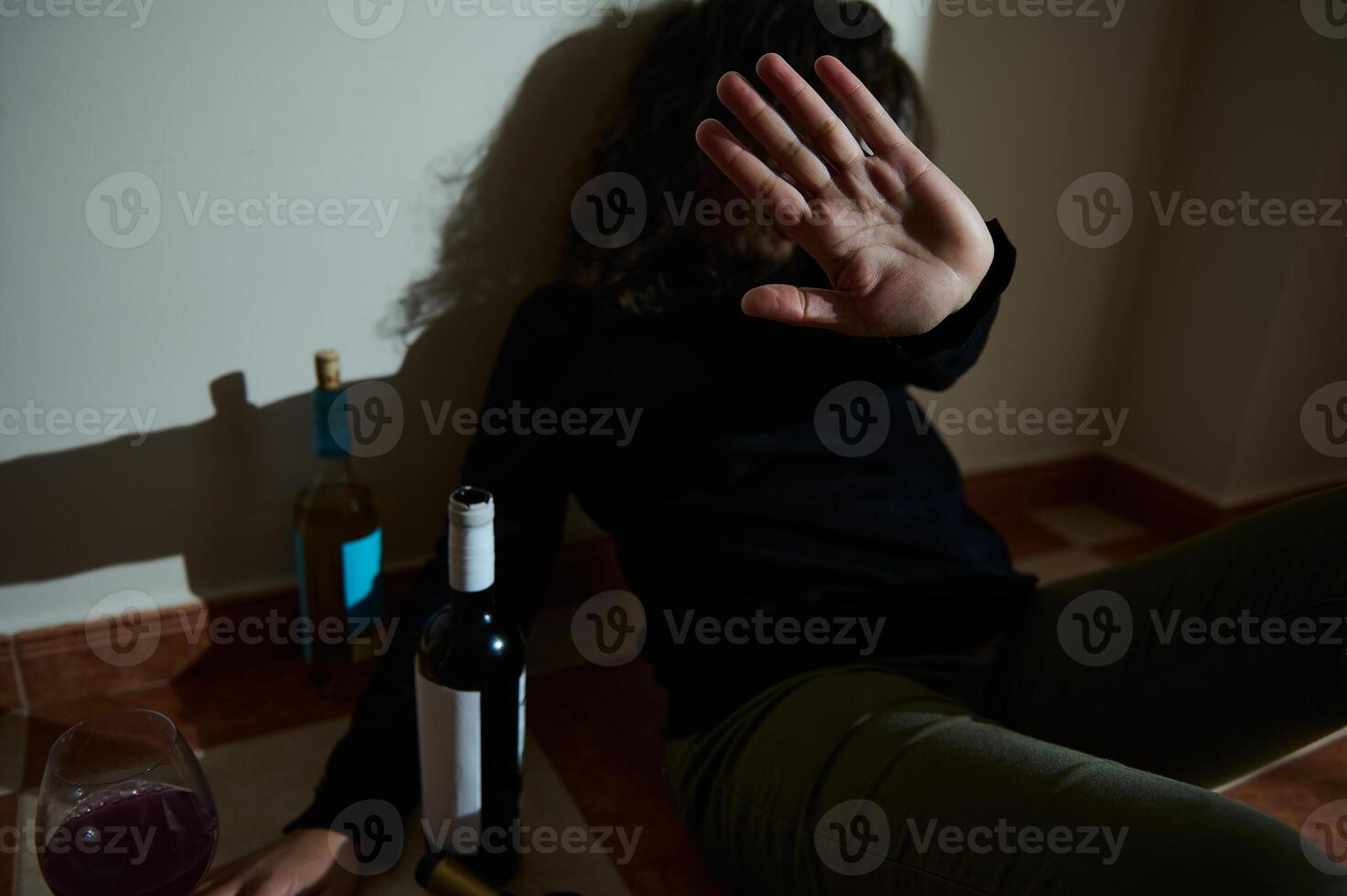 Person displaying rejection near alcoholic bottles, emphasizing struggles and awareness photo