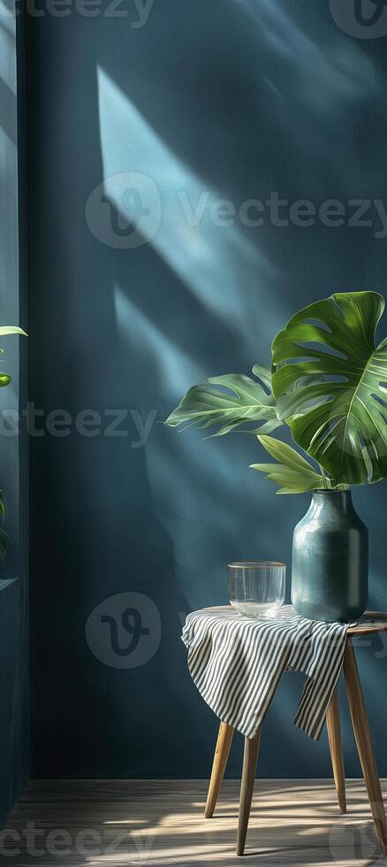 Vase with a monstera leaf on a wooden table against a blue wall photo