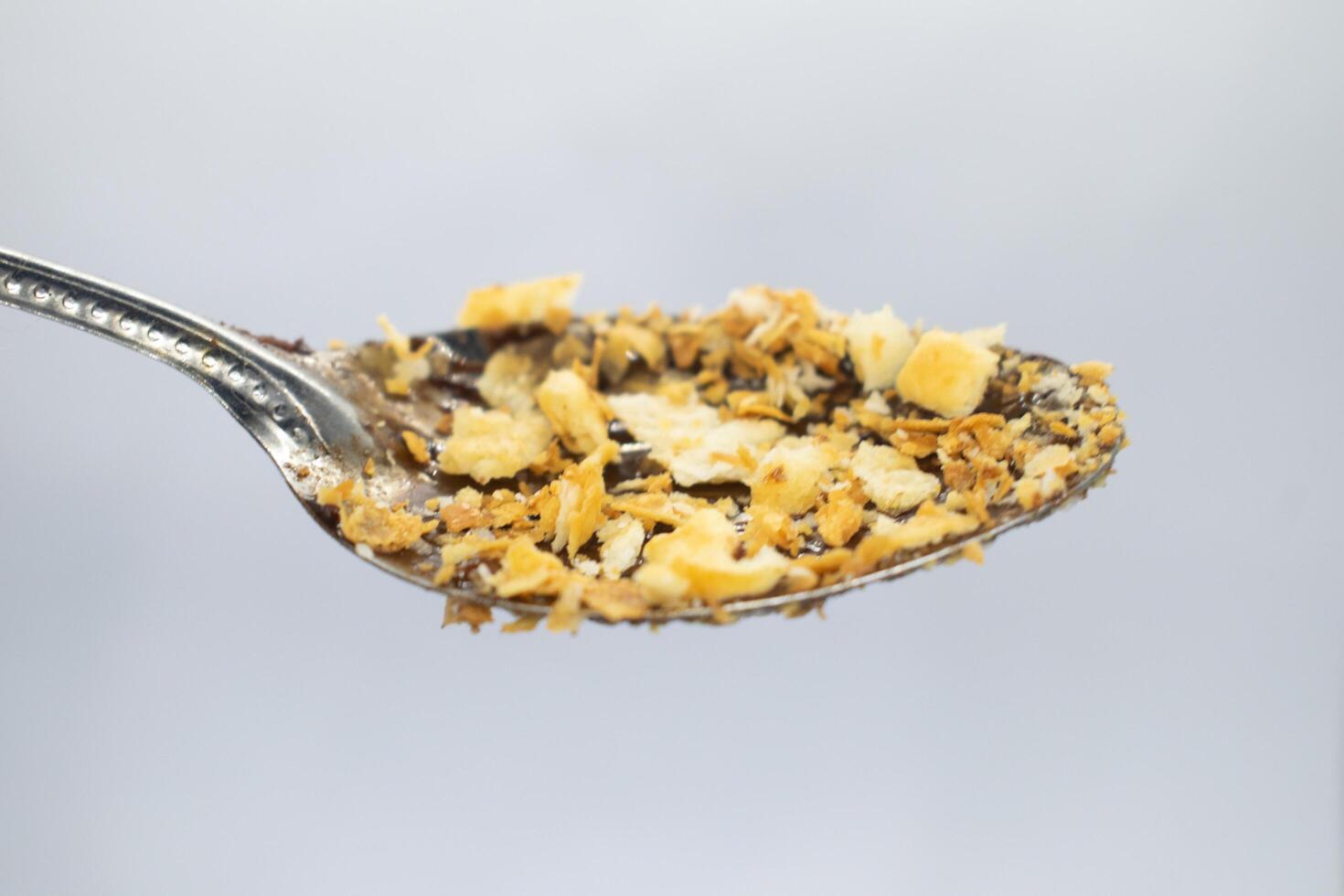 Biscuit flakes stuck to spoon on white background photo