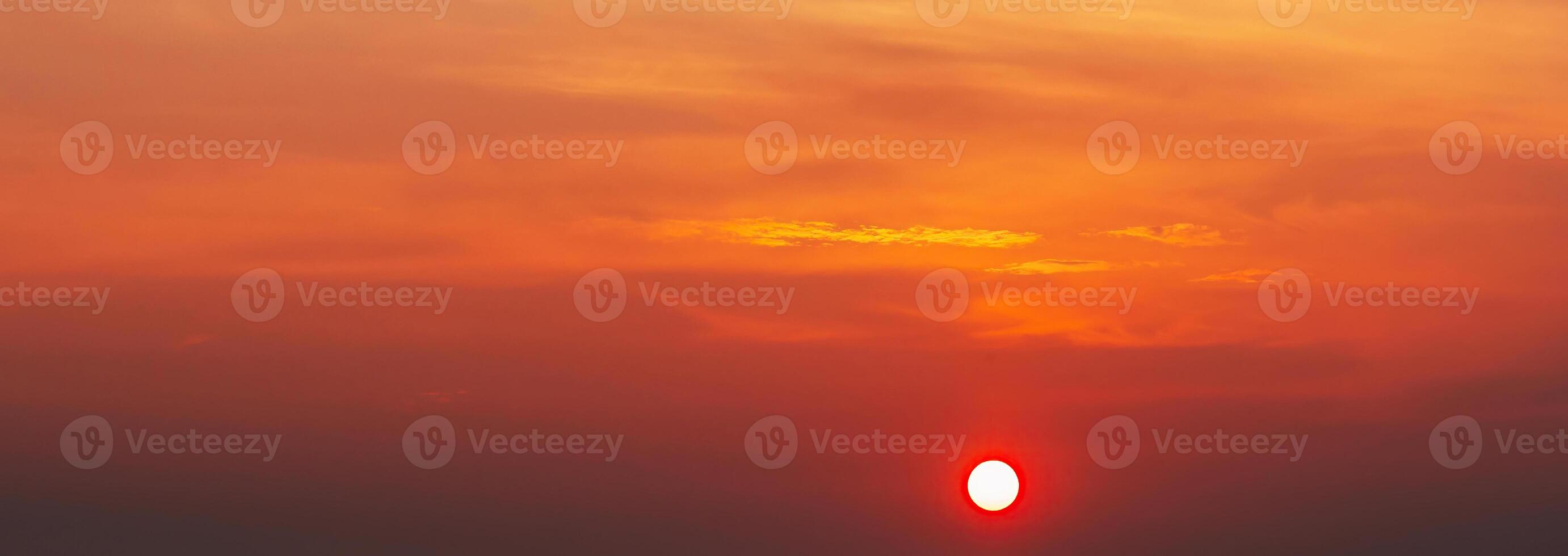 Panorama with an orange sunset and sun in a cloudy sky with clouds. Background with sky at sunrise photo