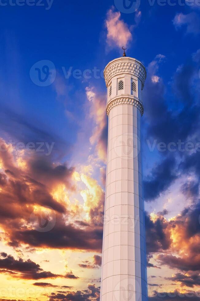 high marble white minaret of the modern new Islamic Masjid Minor Mosque in Tashkent in Uzbekistan on background of sunset sky photo