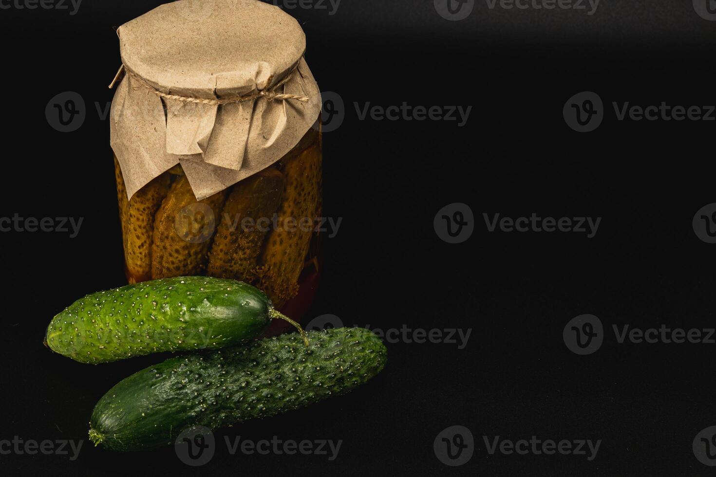 Homemade pickled cucumbers and fresh vegetables on a dark background photo