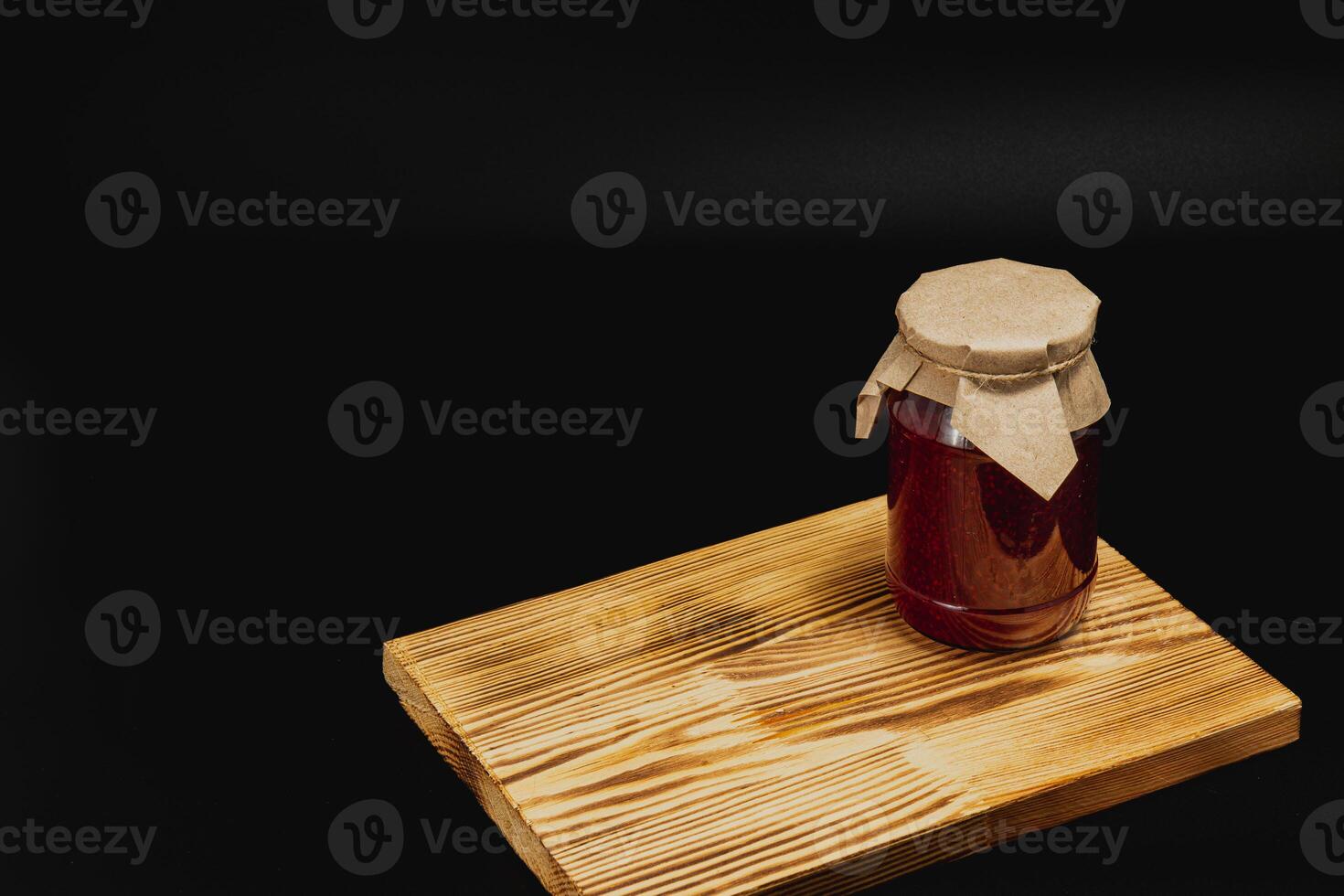 Homemade jam jar with sweet cherries and raspberries placed on wooden board photo