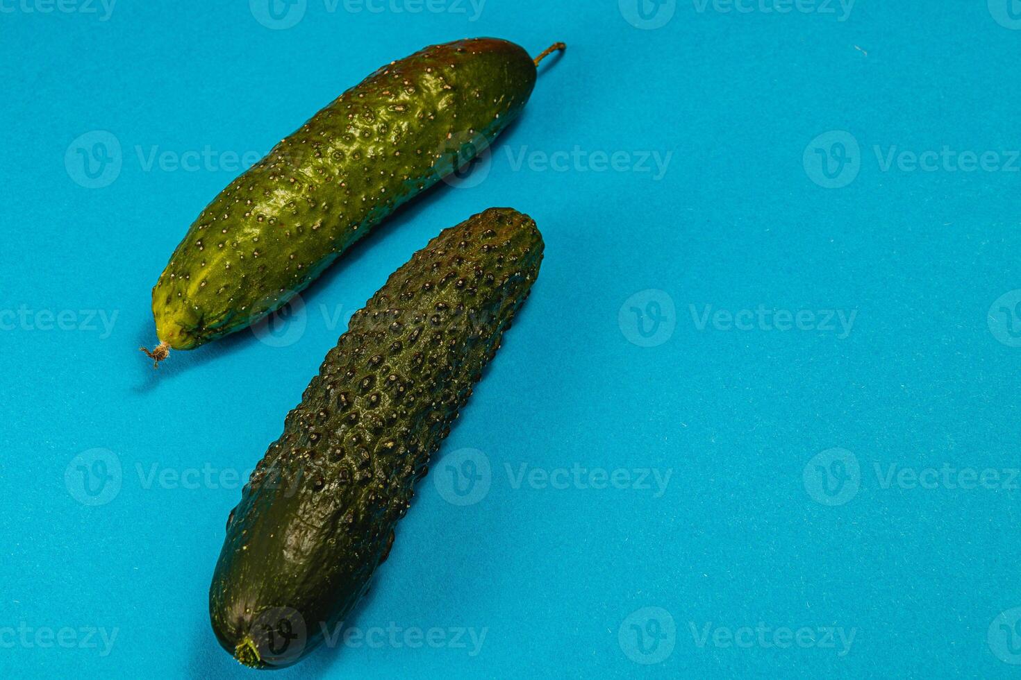 Fresh cucumbers displayed on vibrant blue background for food presentation photo