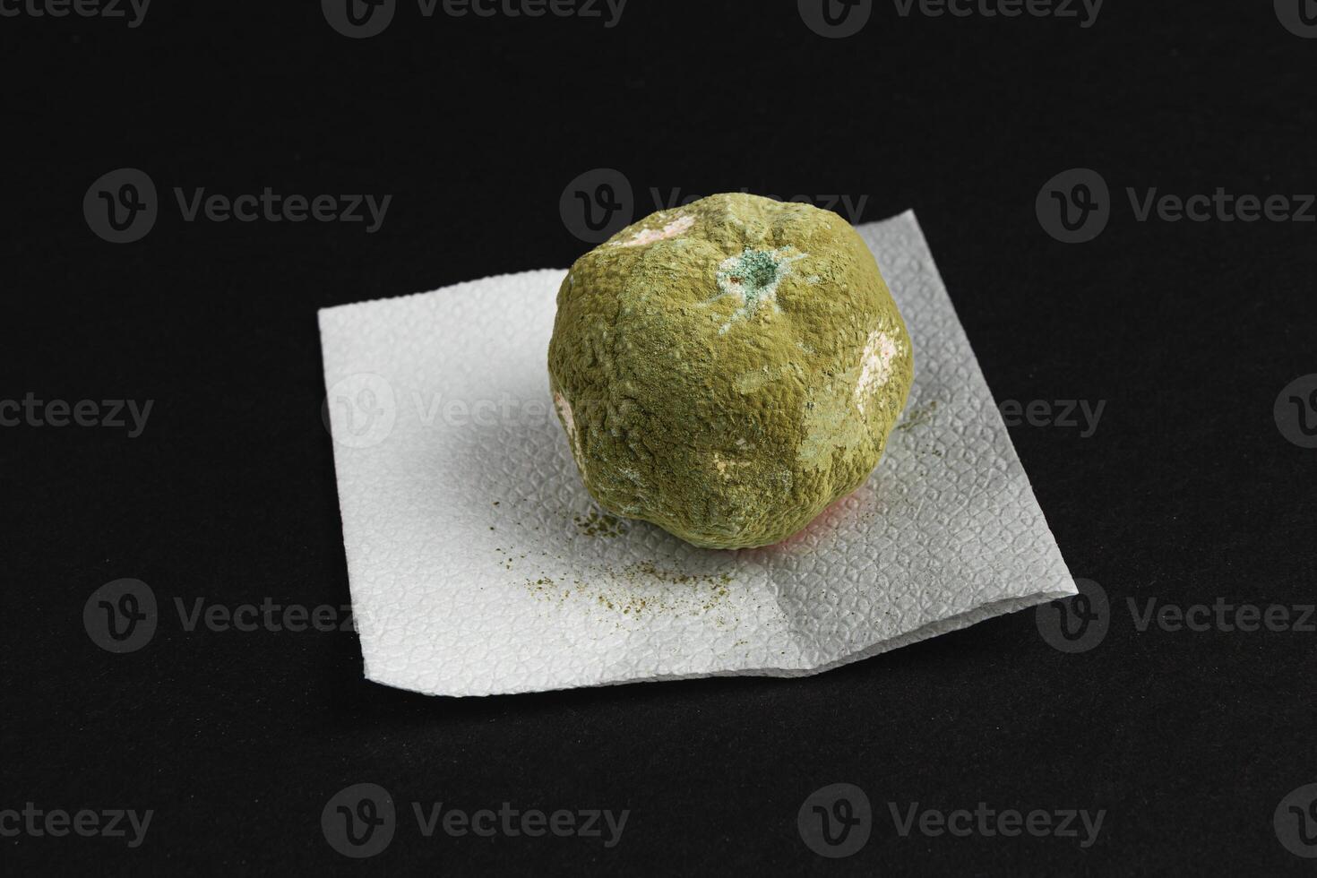 A moldy tangerineresting on a paper towel, showcasing the effects of decay and bacteria photo