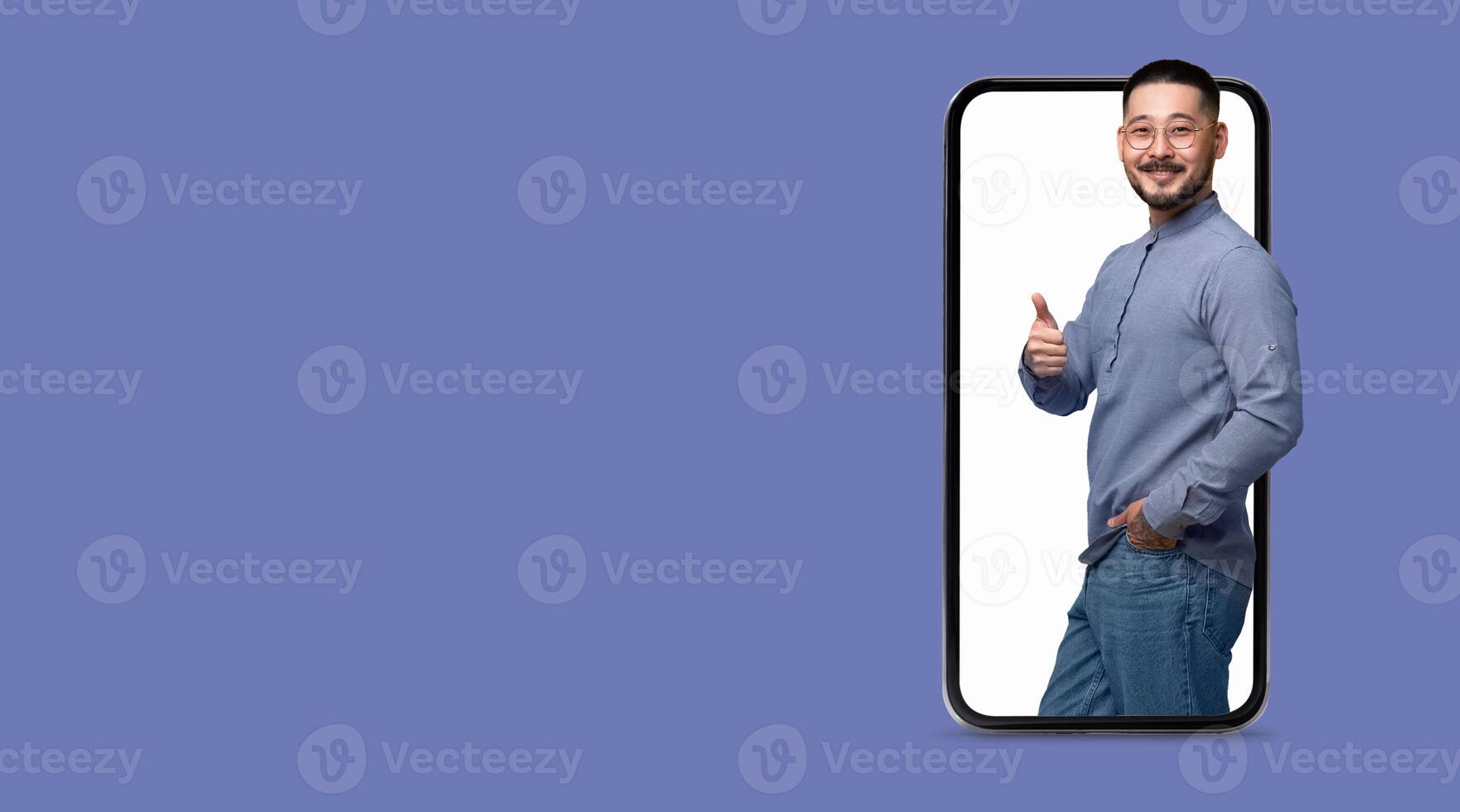 A person stands next to a large smartphone, enthusiastically giving a thumbs up. This moment highlights communication and social media interaction in a modern setting. photo