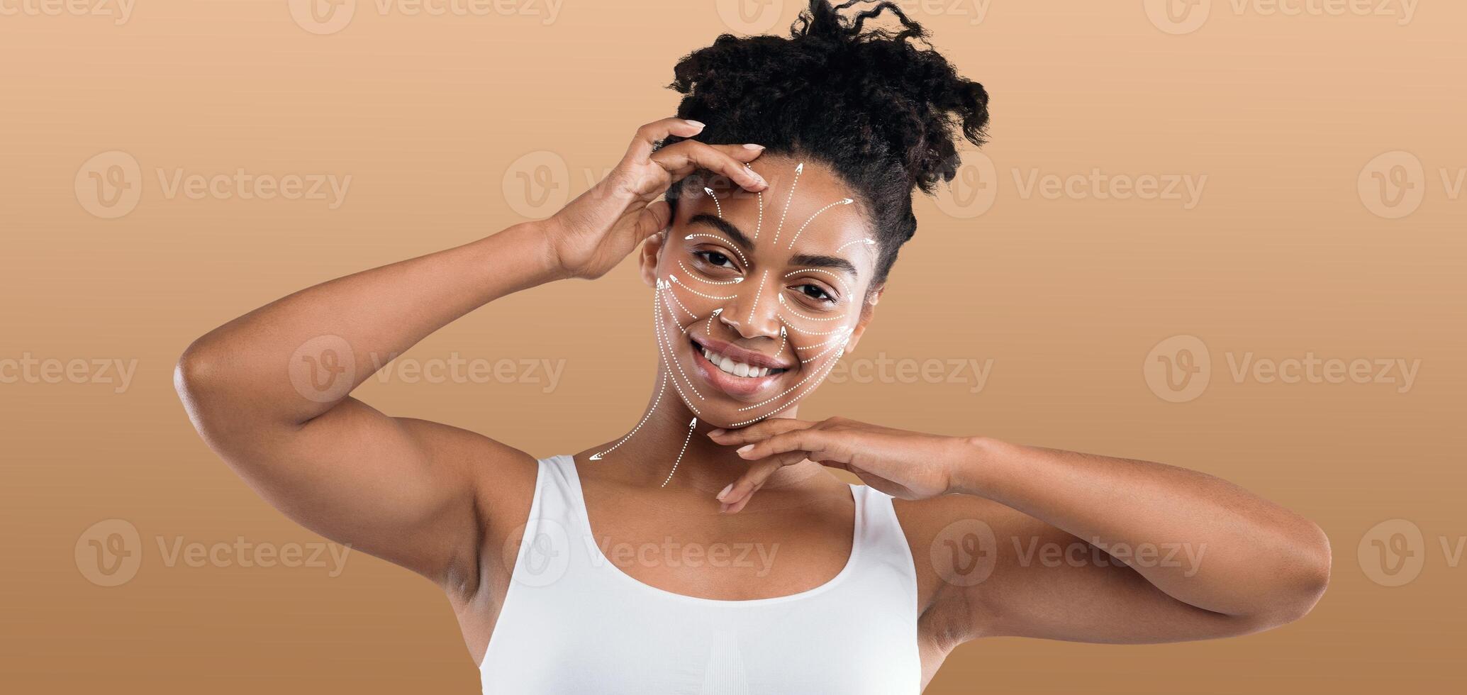 African American woman is engaged in her beauty routine, applying a facial mask with joy. She is in an isolated environment, showcasing the importance of self-care and pampering photo