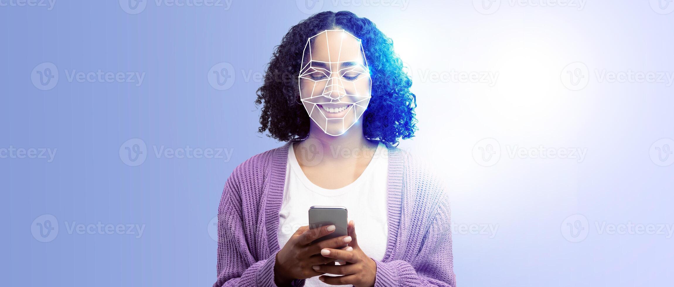 A person is smiling while holding a smartphone in front of them. Their face is illuminated by a digital display, showcasing advanced face recognition technology in use. photo