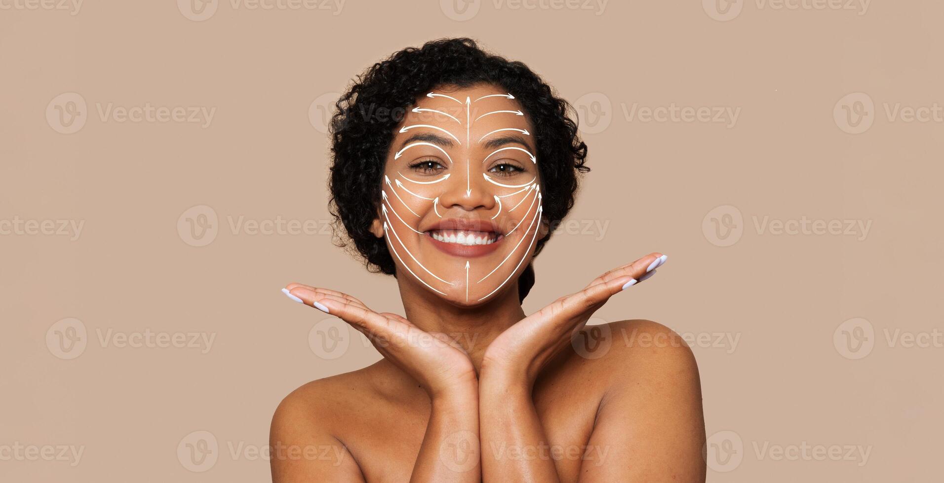 A woman smiles brightly while showcasing her skin care routine. Her face is adorned with beauty patterns, emphasizing a moment of self-care and relaxation in a neutral atmosphere. photo