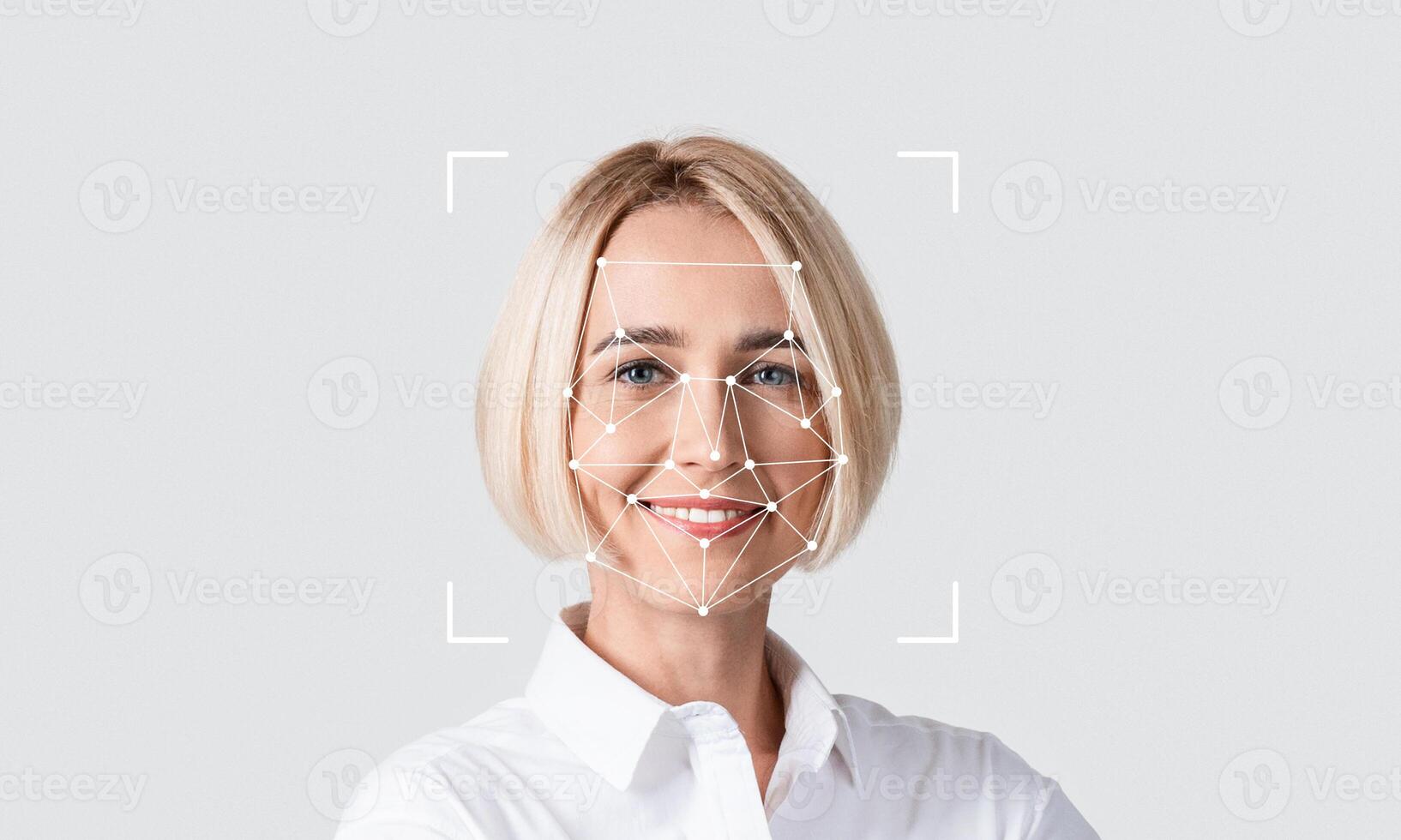 A woman smiles confidently while demonstrating facial recognition technology. The digital overlay highlights key facial features for identification purposes. photo