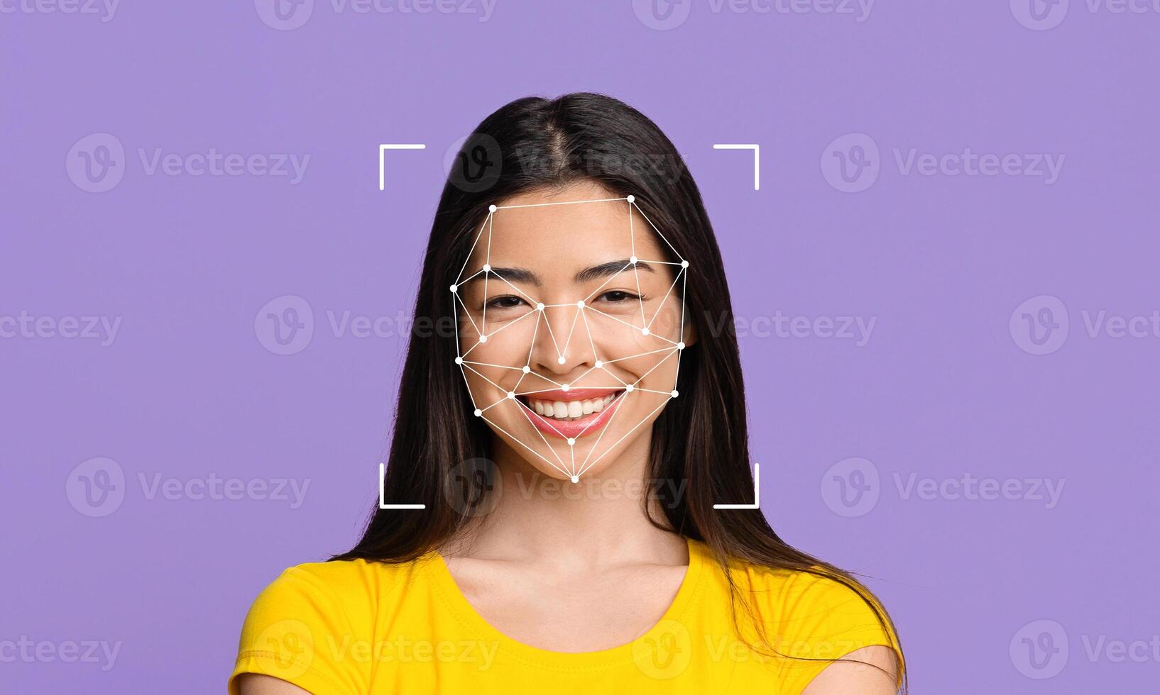 A woman with long dark hair is smiling at the camera, wearing a yellow shirt. photo