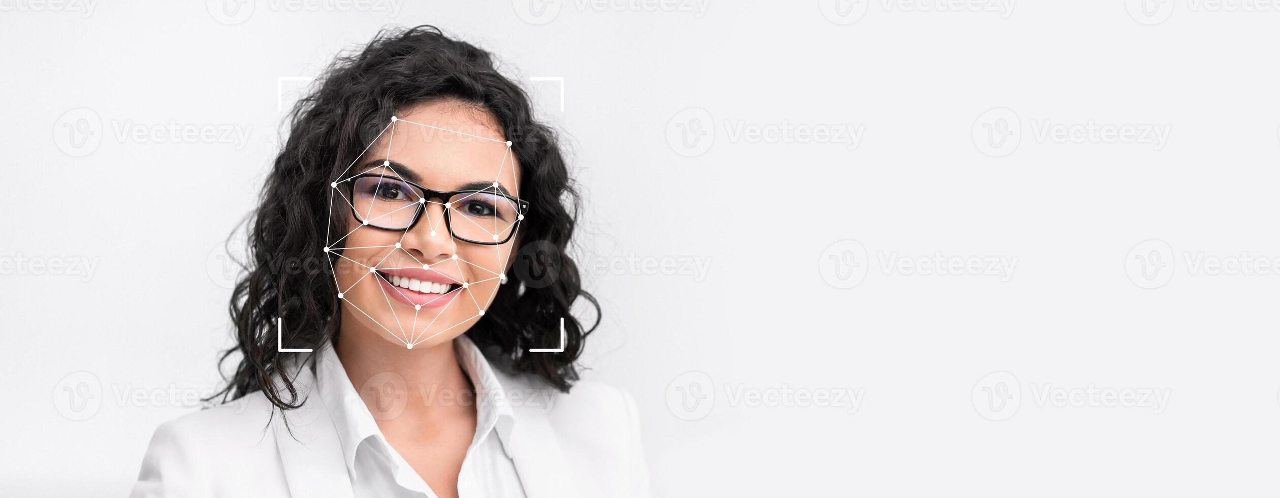 A woman with curly hair and glasses smiles confidently while facial recognition technology captures her features. The background is minimalistic and focused on her expression. photo