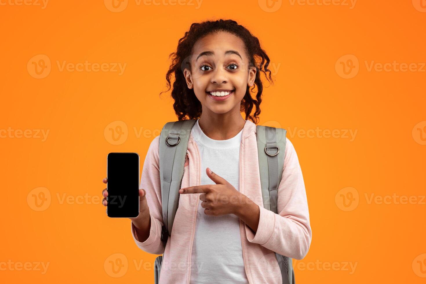 Mobile Application Ad. Portrait Of Excited African Girl Showing Phone Empty Screen Recommending App Standing Over Yellow Studio Background, Smiling To Camera. Cellphone Display Mockup, Check This Apps photo