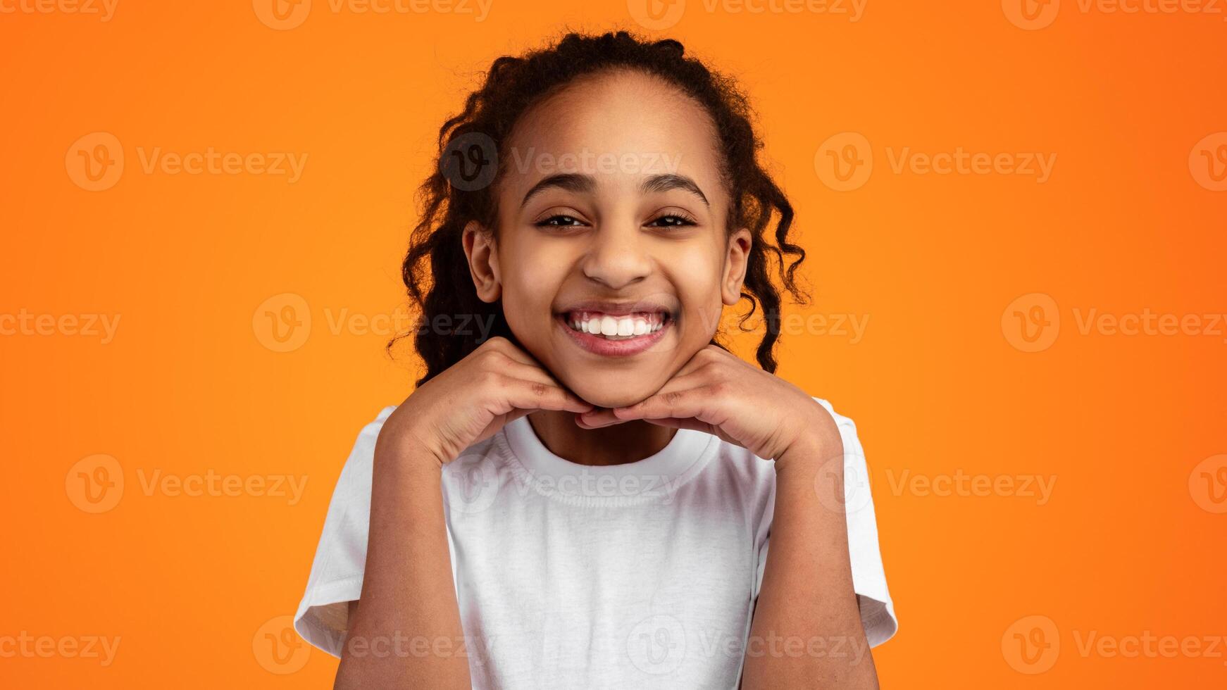 Portrait Of Cute Joyful African American Girl Leaning Chin On Hands And Smiling At Camera, Young Child Posing Isolated Over Yellow Studio Background With Copy Space, Banner, Panorama photo